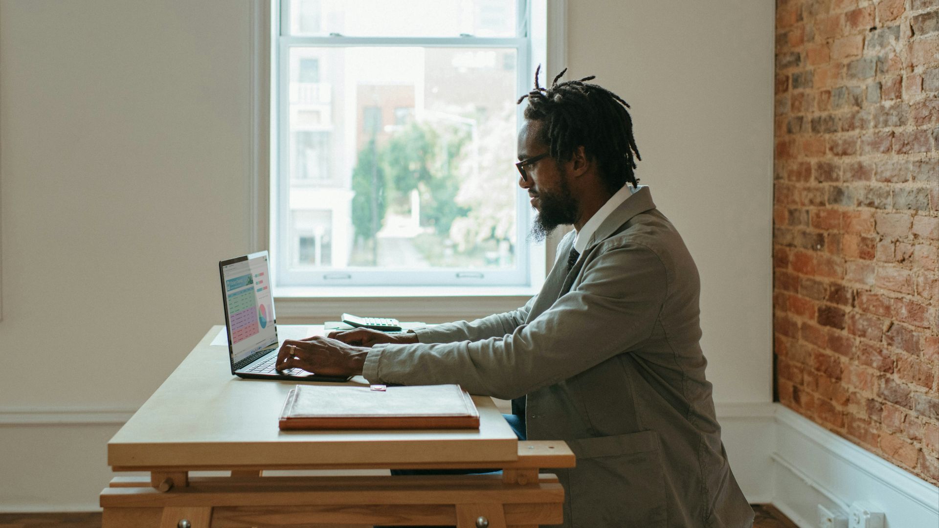 a person sitting at a desk with a laptop and papers