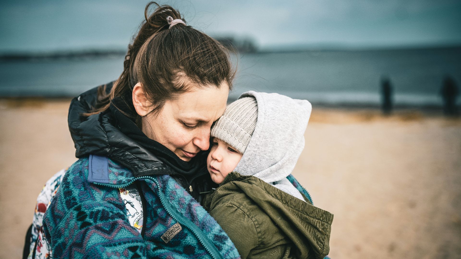a woman holding a child on the beach