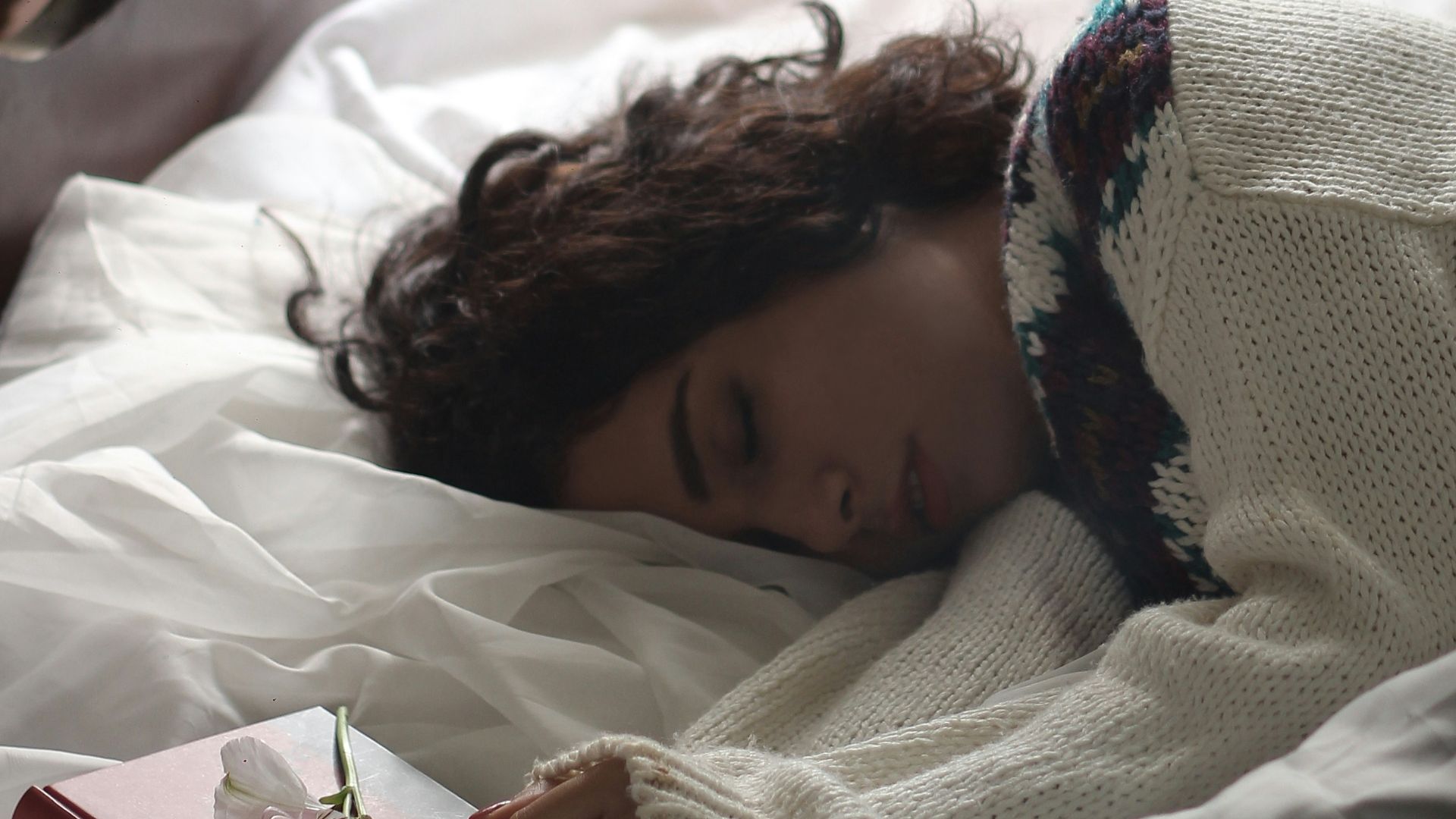 woman sleeping on bed beside book