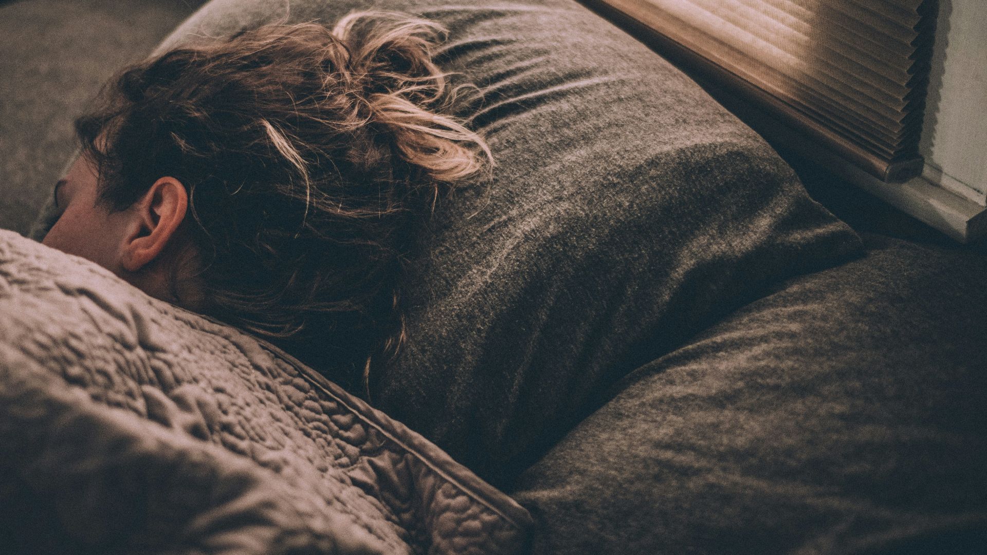 woman sleeping on bed under blankets