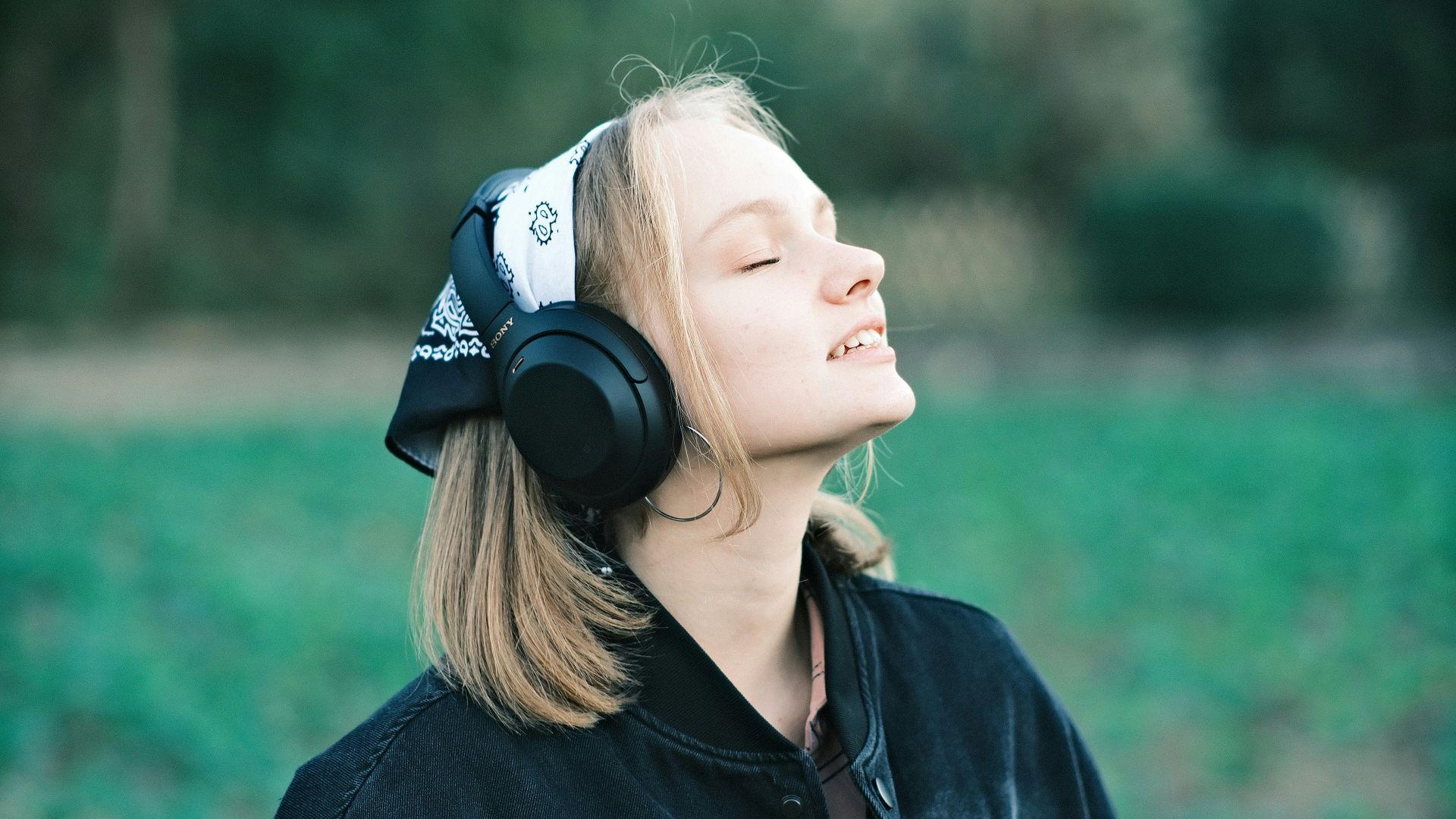 a woman wearing headphones in a field of grass