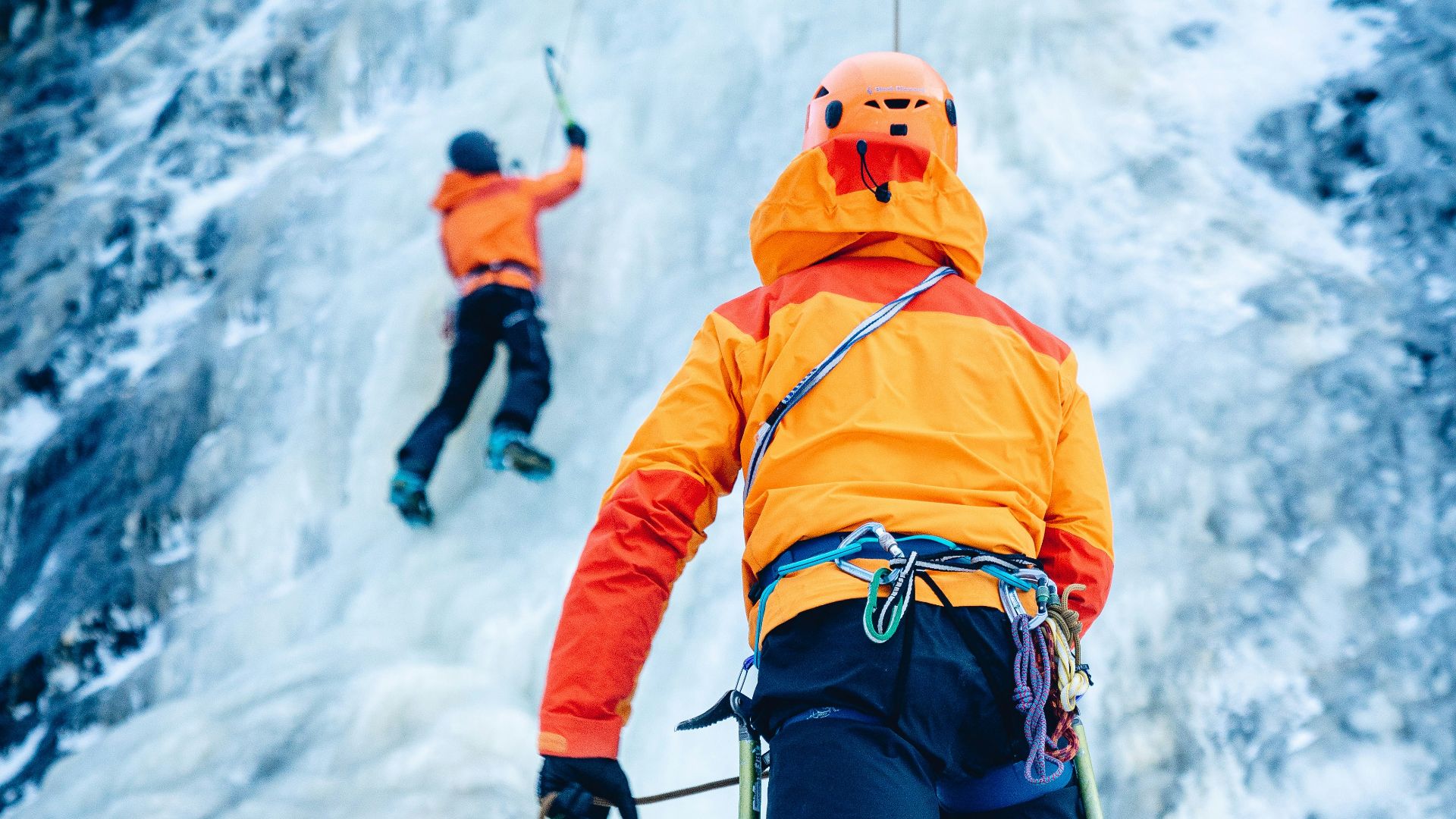 person in orange jacket and blue pants standing on rocky hill during daytime