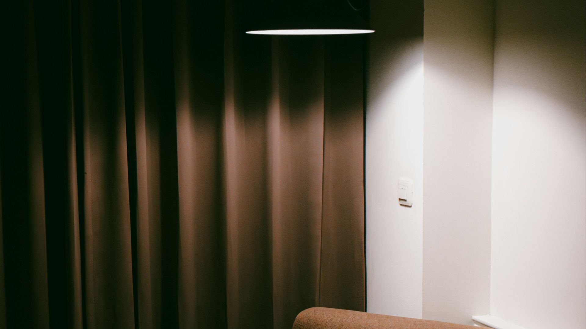 A lit armchair is sitting in a darkened corner.