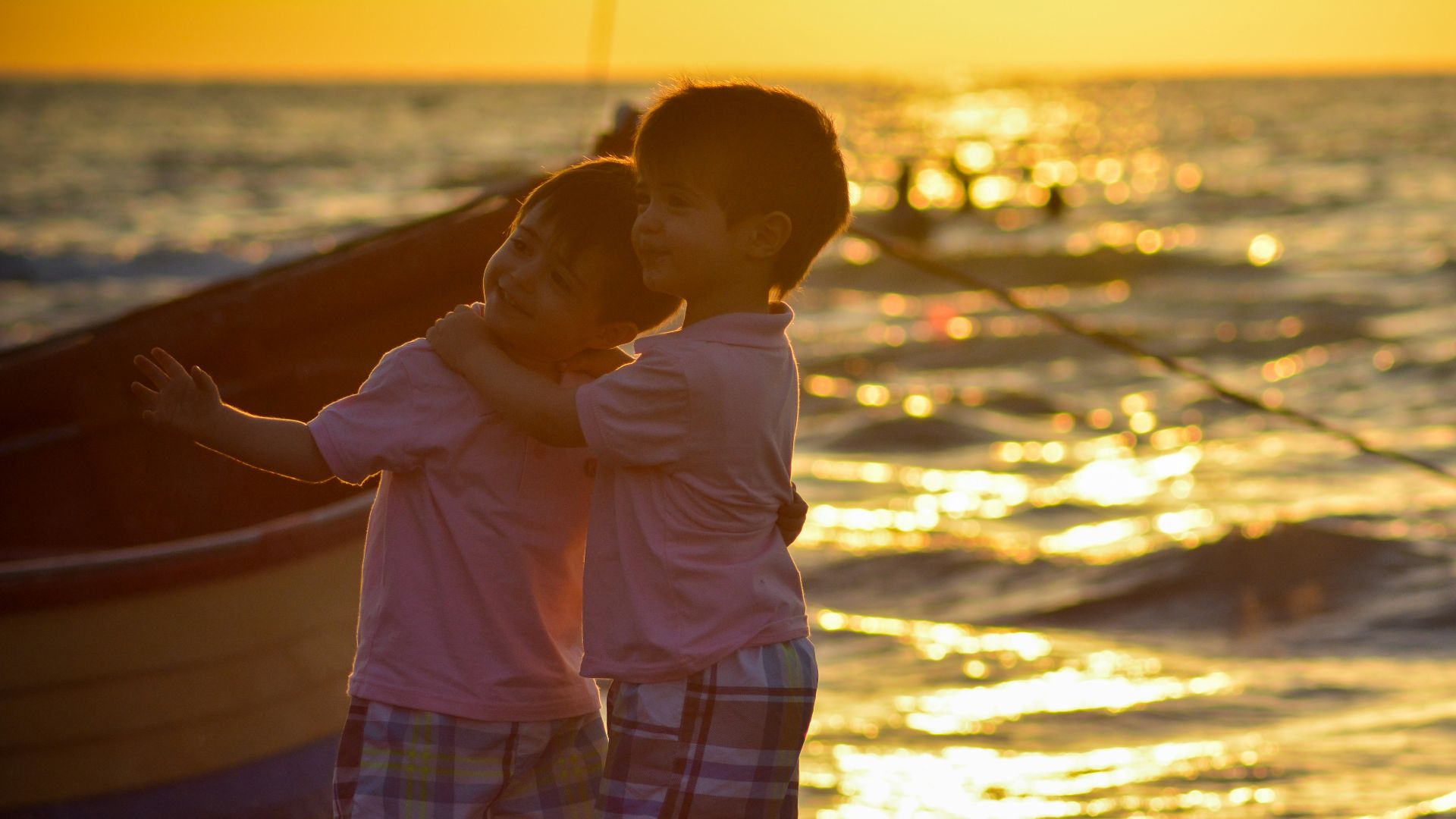 two boys standing on seashore during sunset