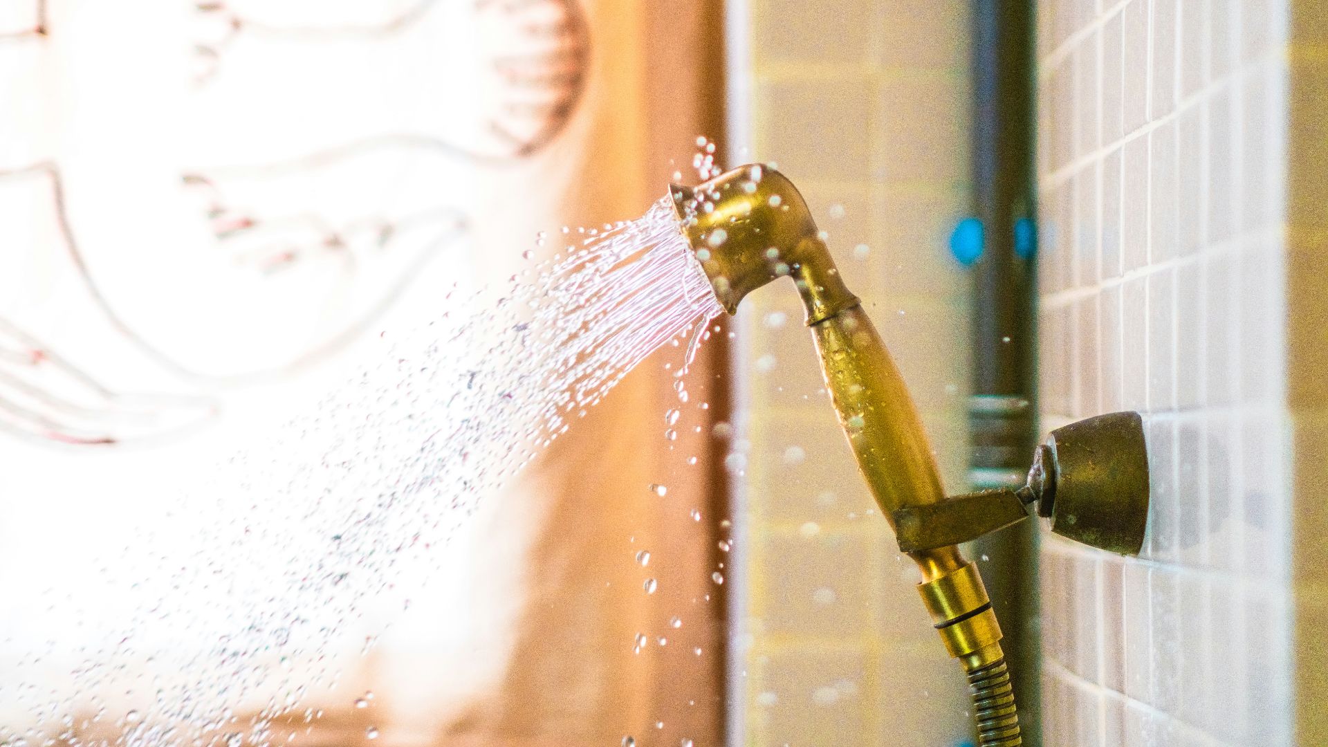 a shower head spraying water onto a tiled wall