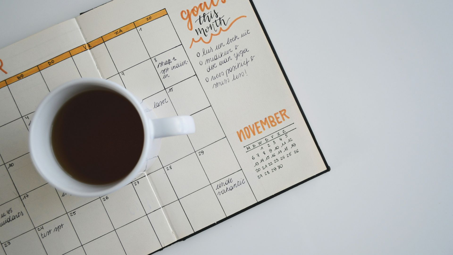white ceramic mug with coffee on top of a planner