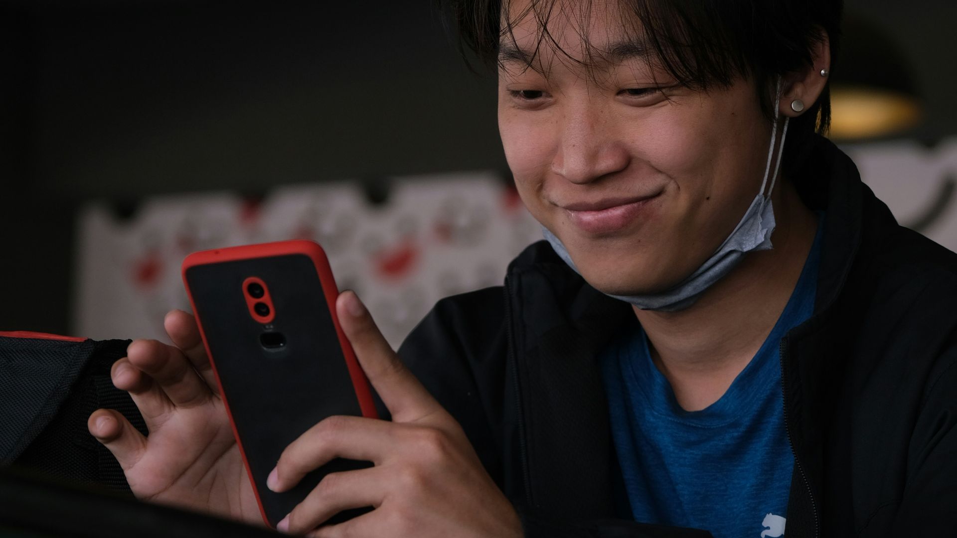boy in blue and black jacket holding black smartphone