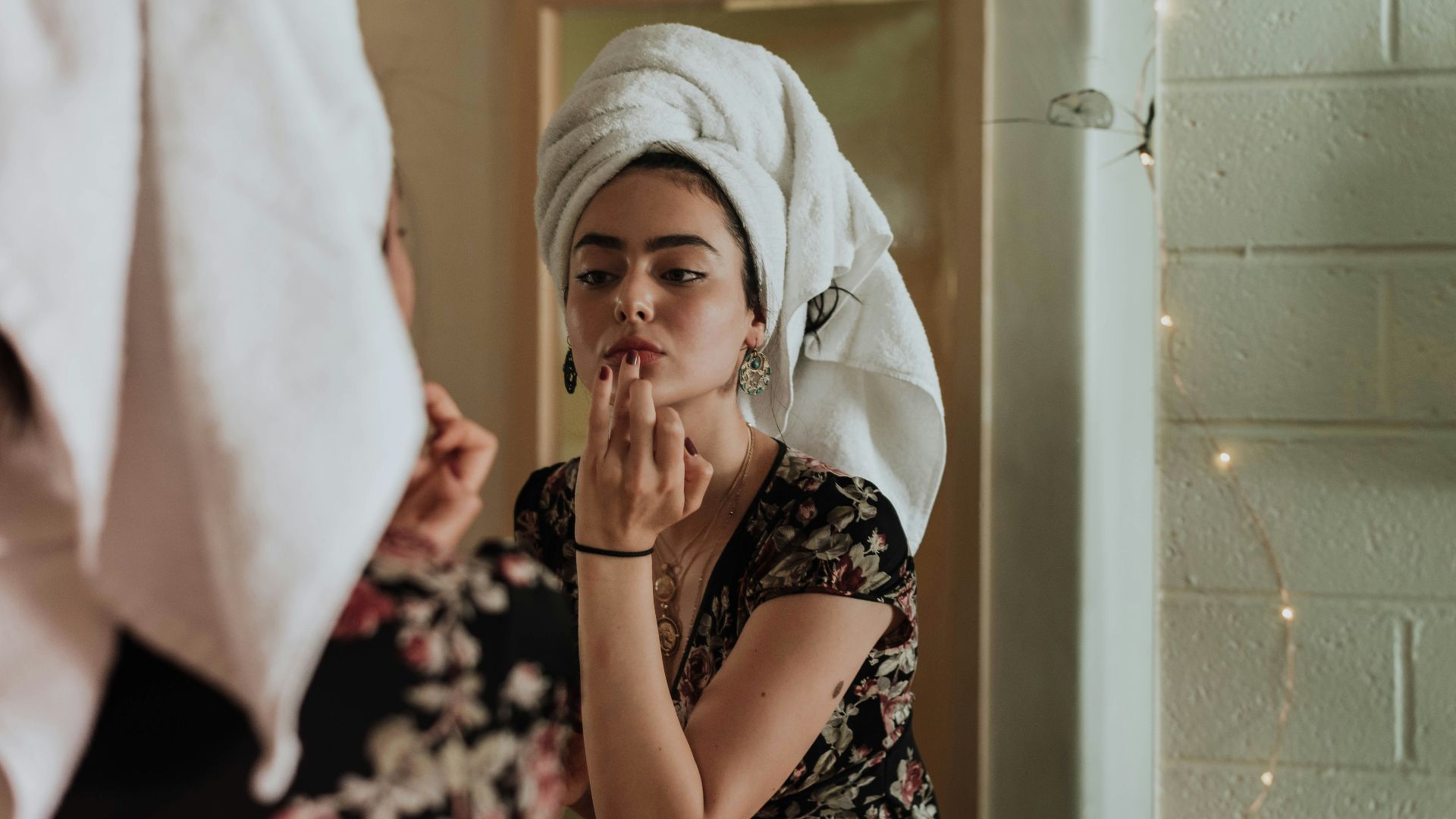woman putting makeup in front of mirror