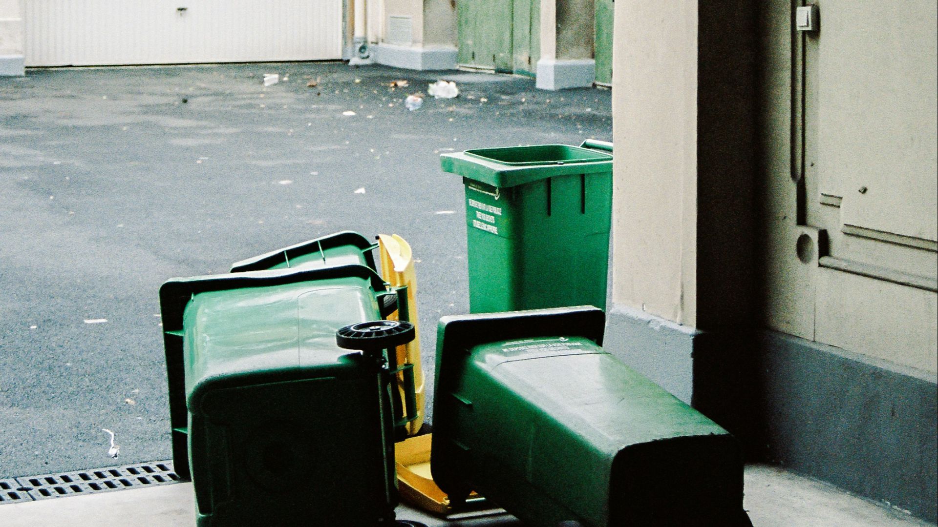 green trash bin beside white wooden door