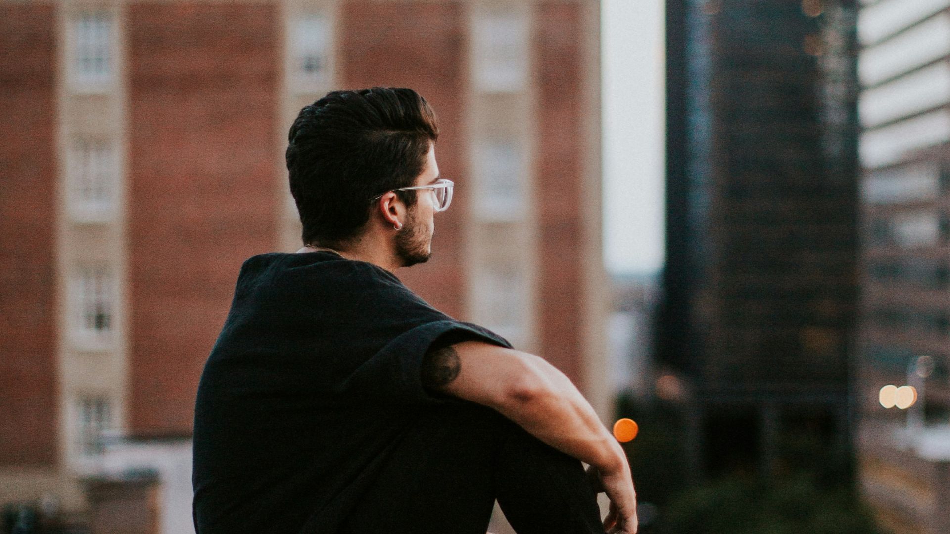 man sitting on white concrete building during daytime