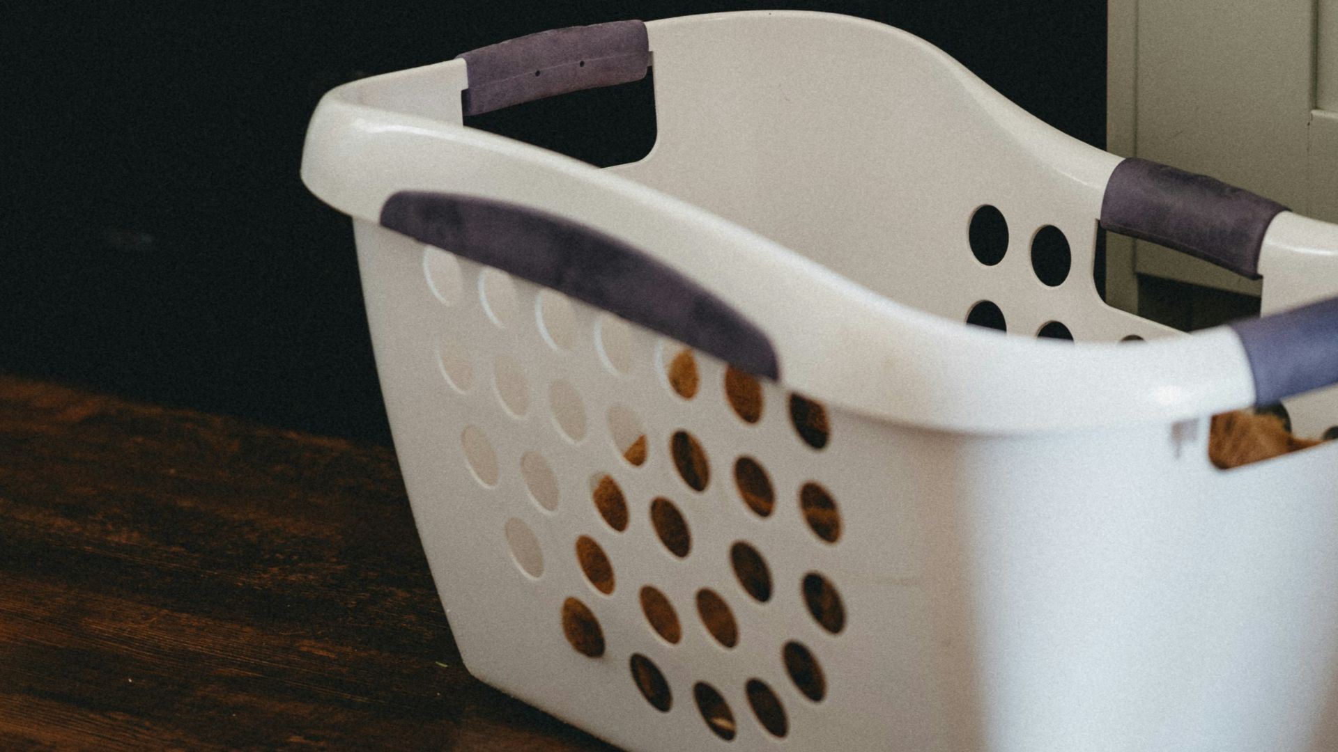 white plastic laundry basket beside black front load washing machine