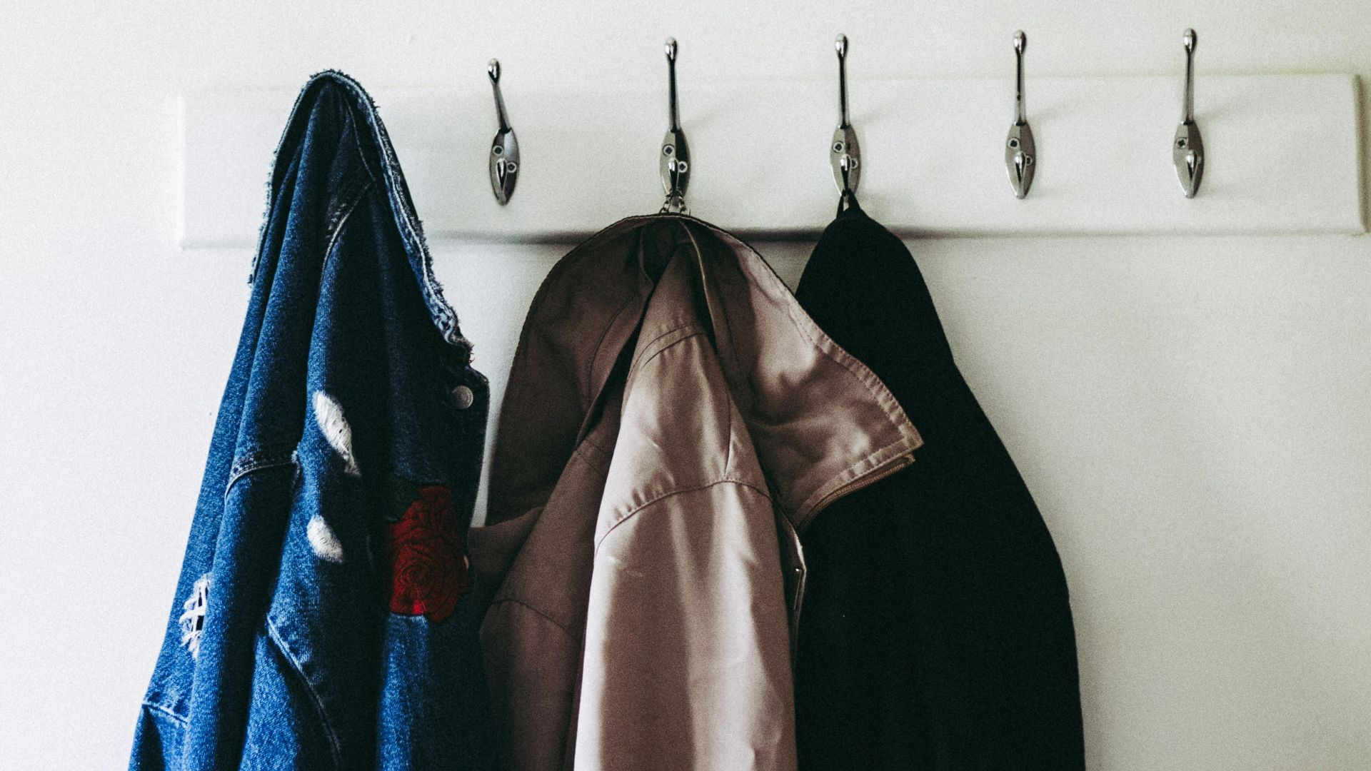 three jacket hanging on wall hooks