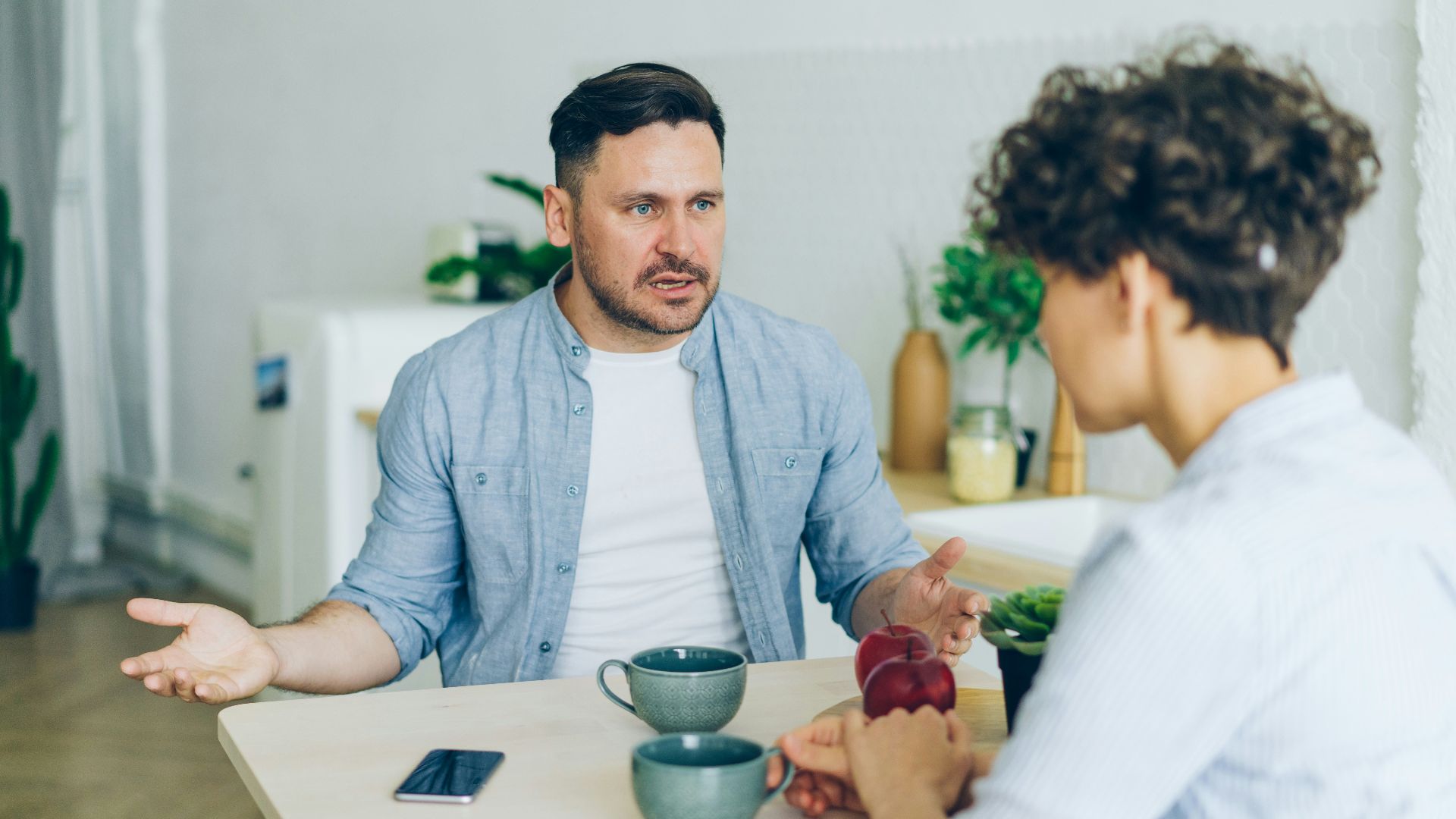 a man sitting at a table talking to a woman