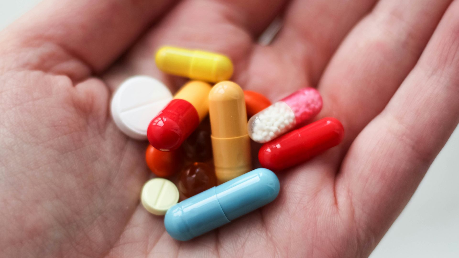 orange and white medication pill on persons hand