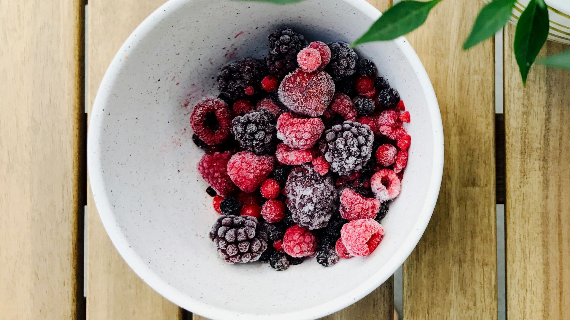 raspberries and black berries in white ceramic bowl