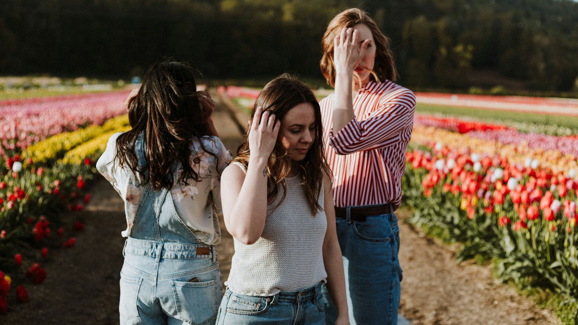three women standing between flower garden