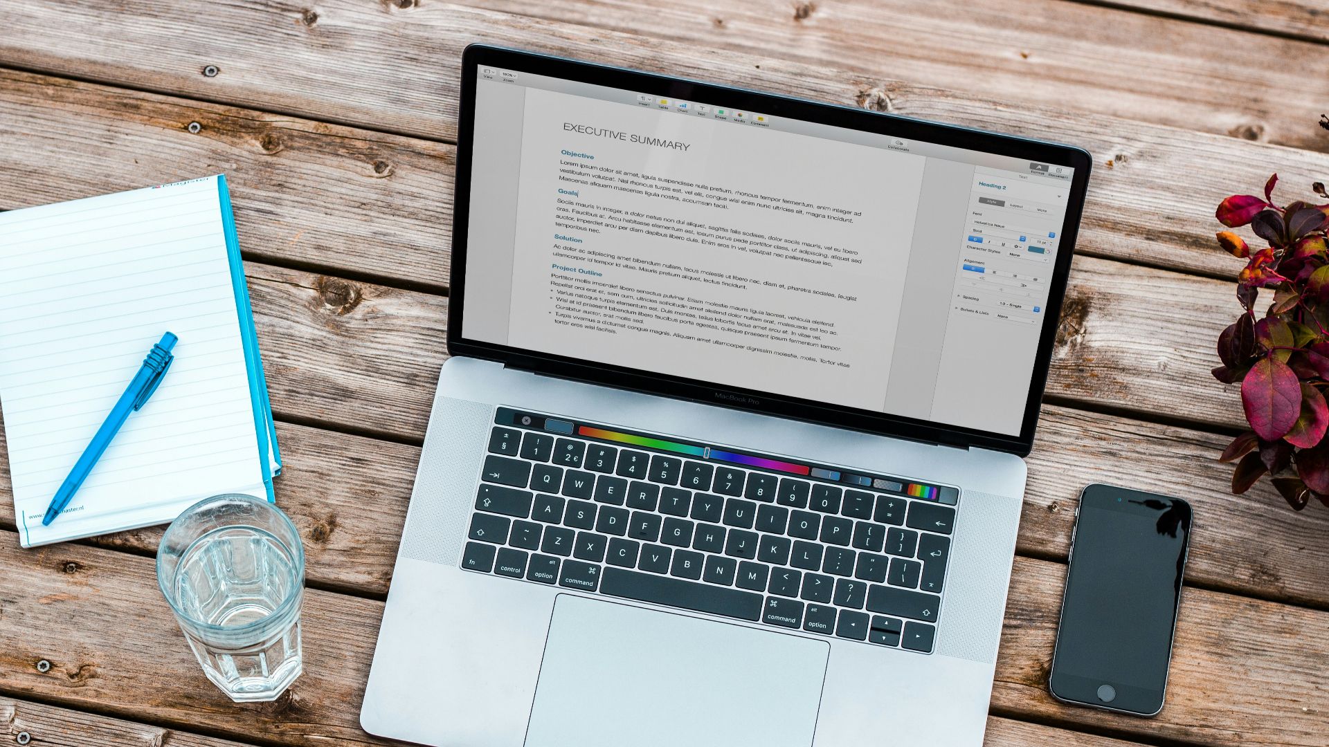 silver MacBook beside space gray iPhone 6 and clear drinking glass on brown wooden top