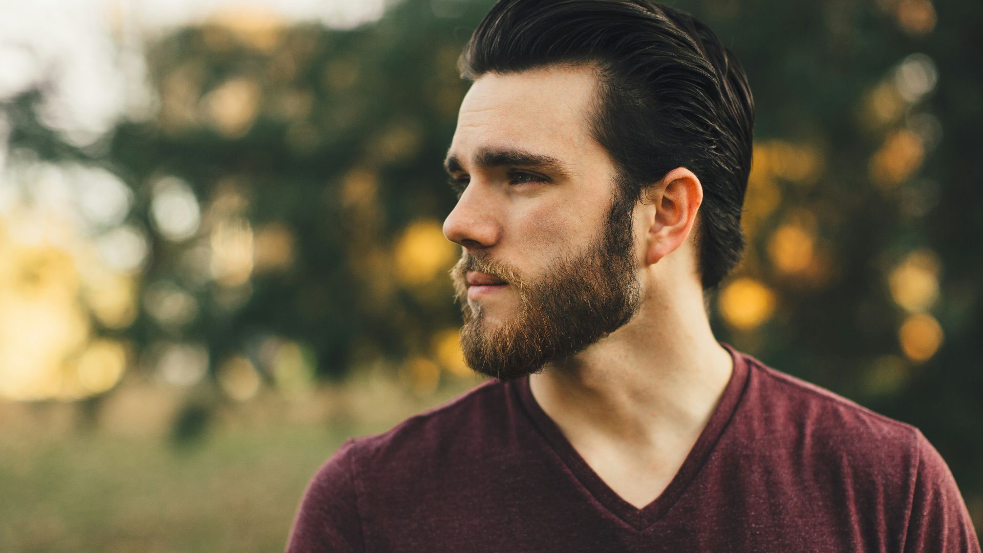 man wearing maroon V-neck t-shirt in forest
