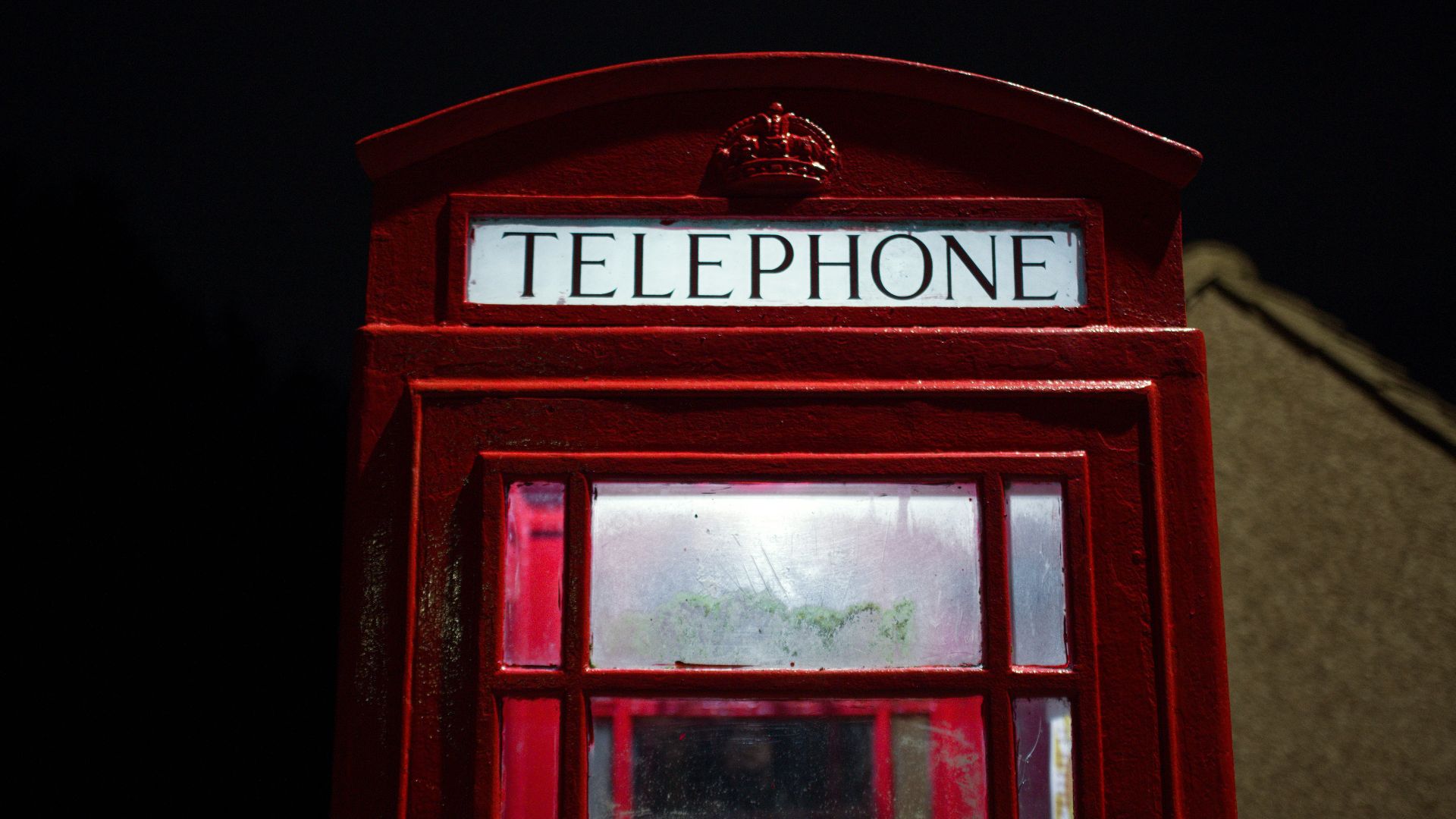 a red telephone booth sitting in the dark