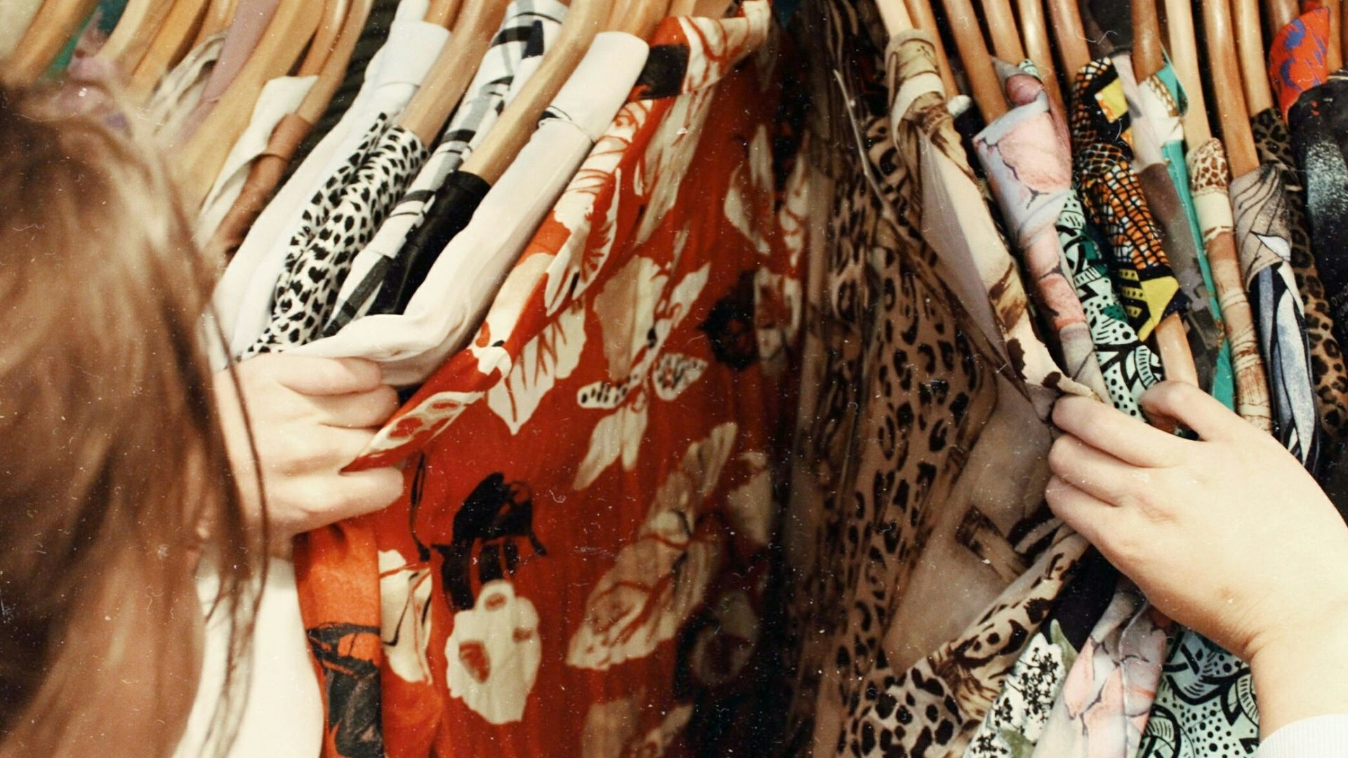 person holding assorted clothes in wooden hanger