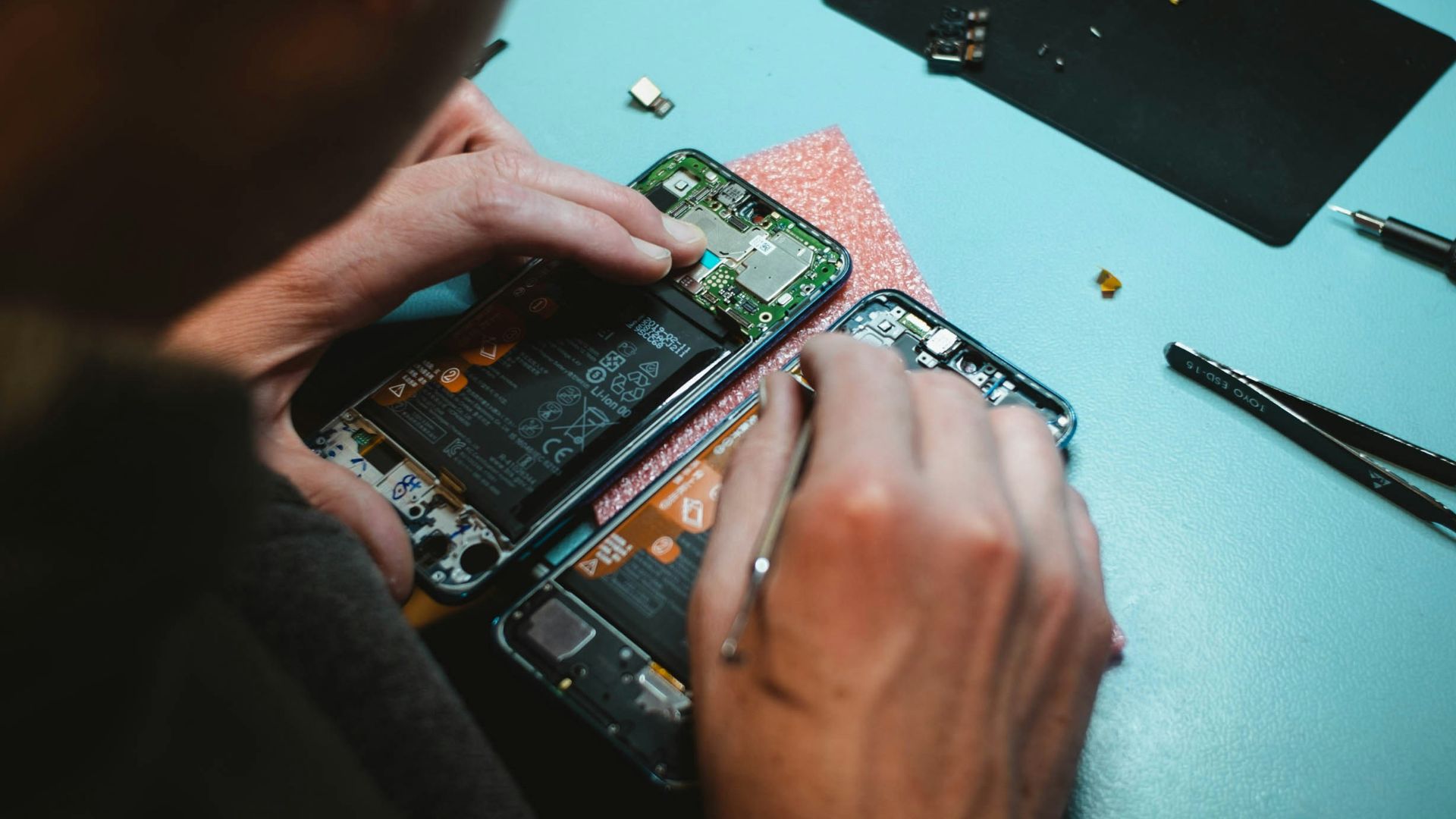 person repairing smartphones under a lighted table