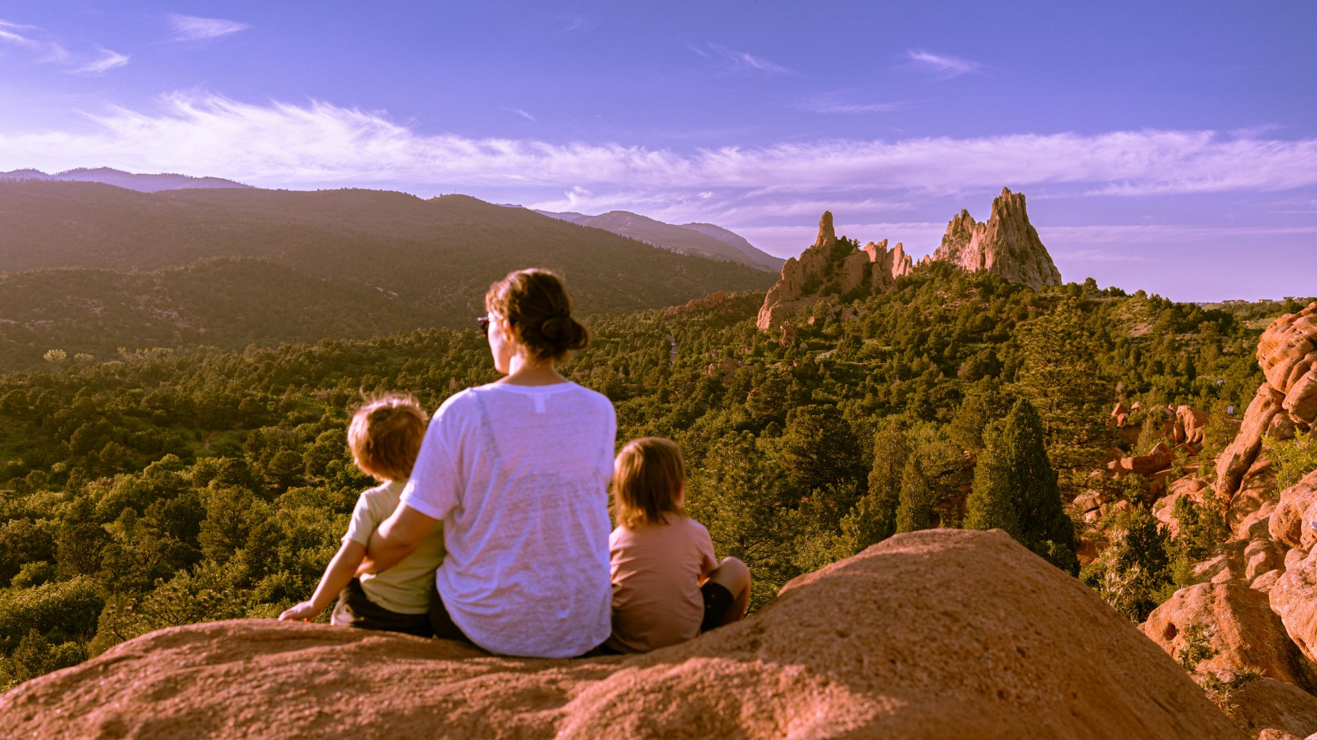a man and two children sitting on top of a rock