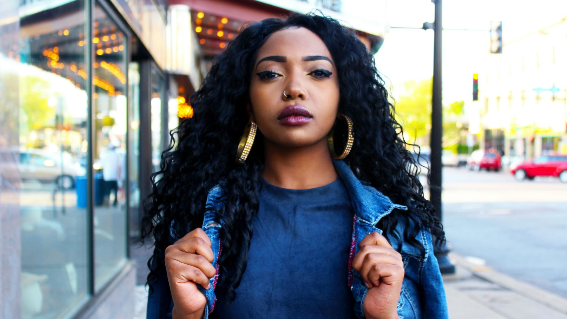 women holding denim jacket near glass window