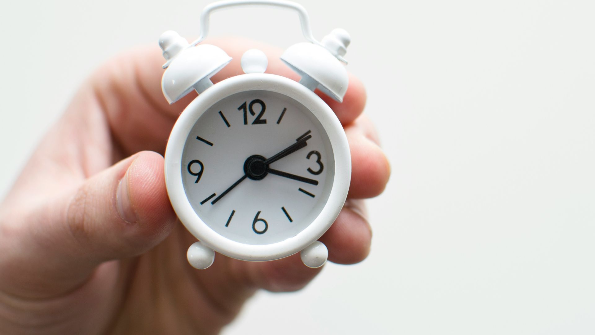 person holding white mini bell alarmclock