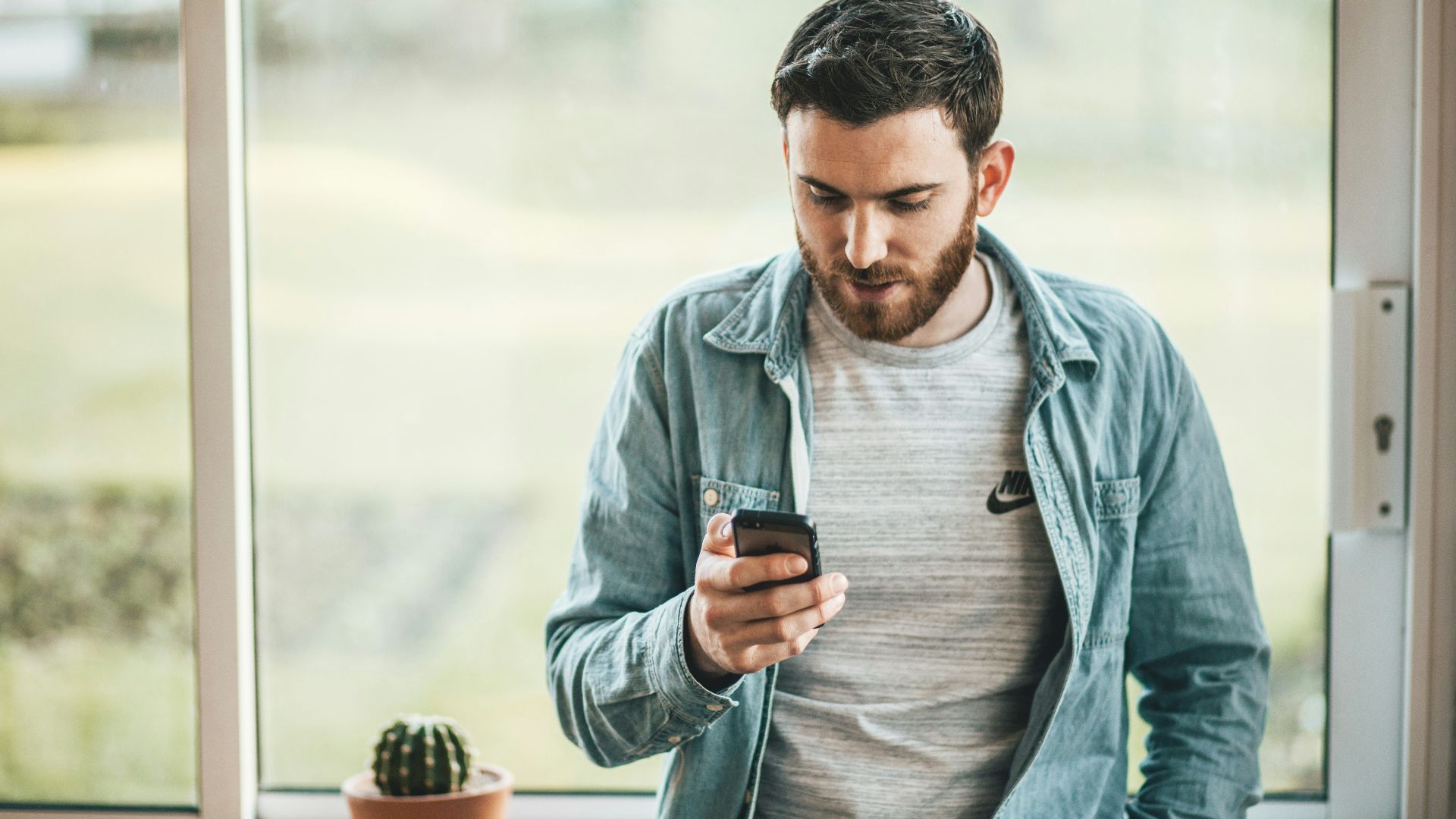 man holding a smartphone near the window