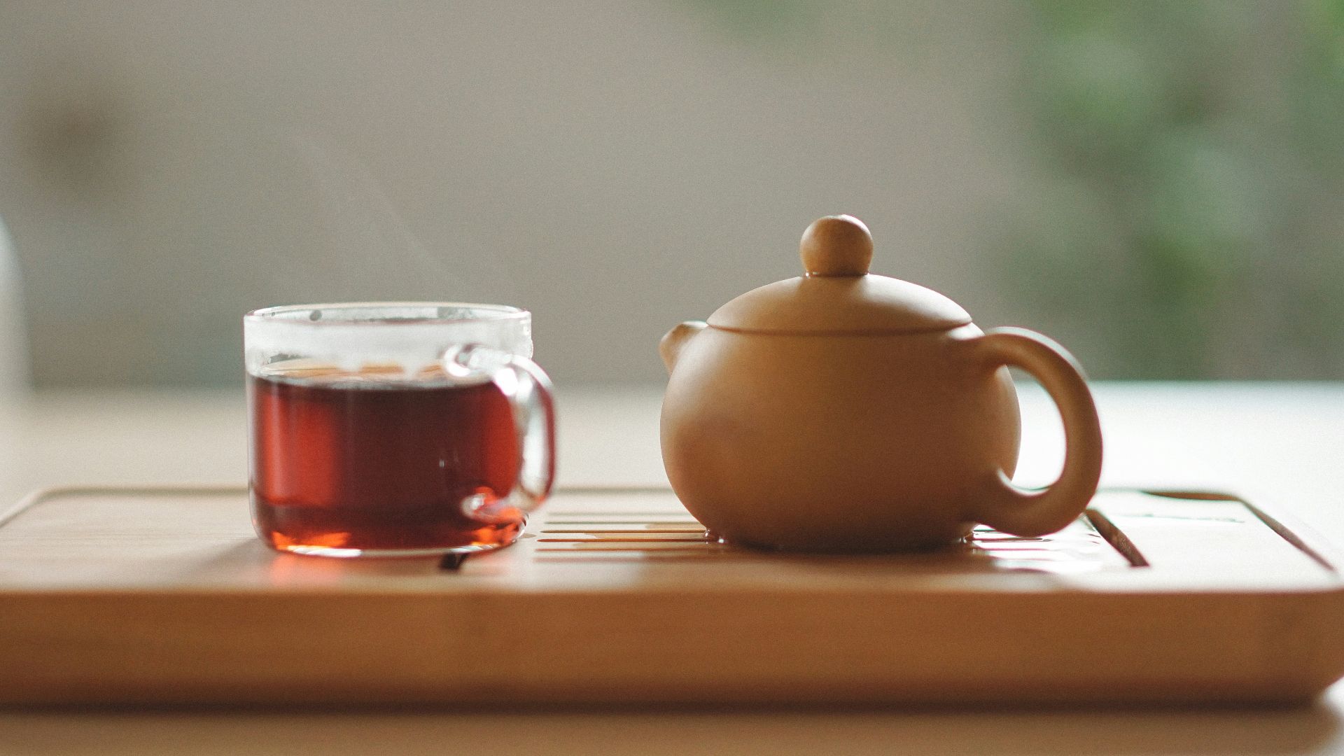 clear glass cup with tea near brown ceramic teapot