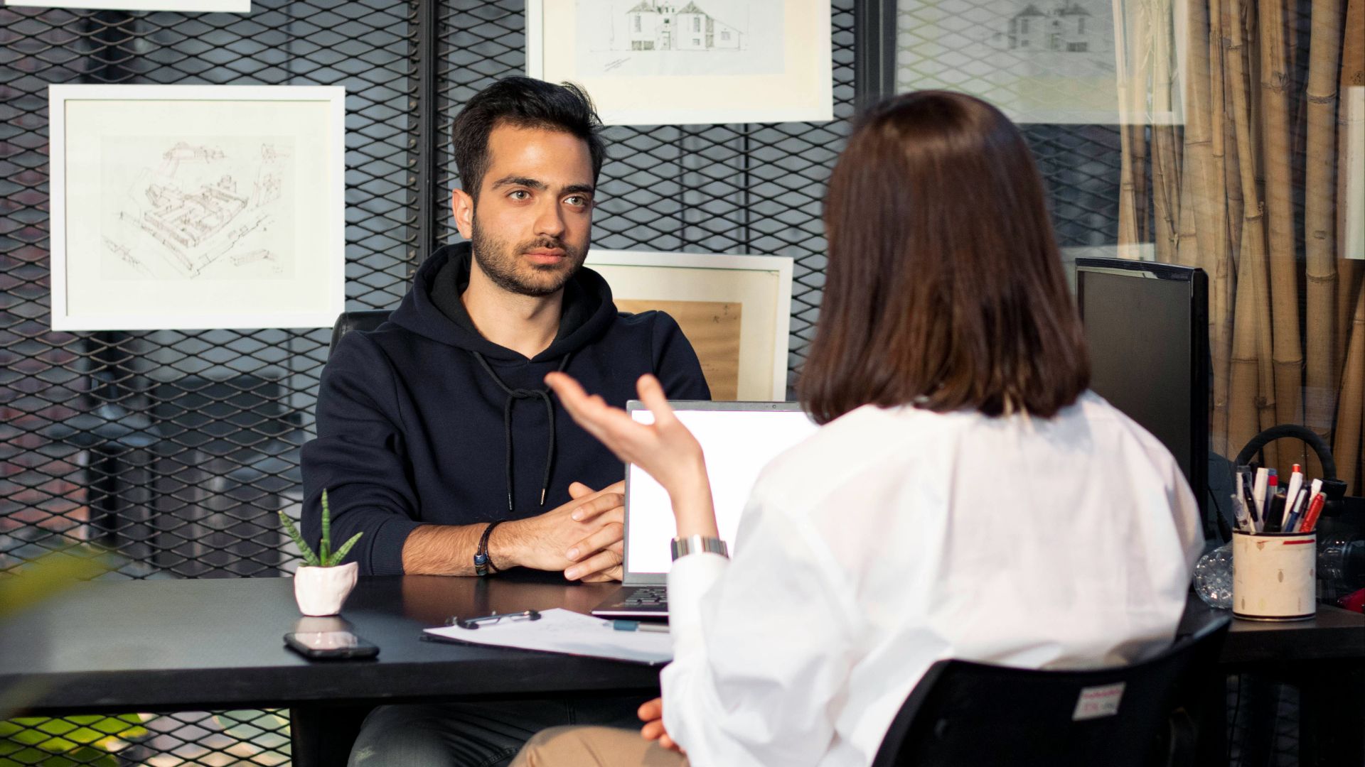 a man sitting at a desk talking to a woman