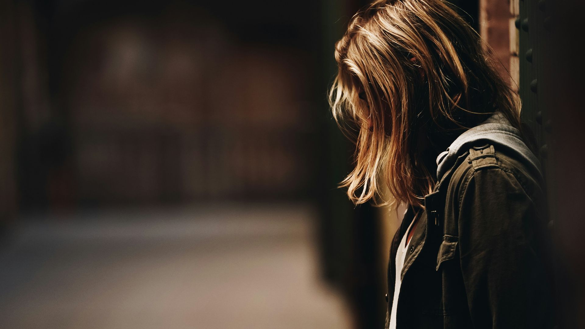 woman leaning against a wall in dim hallway