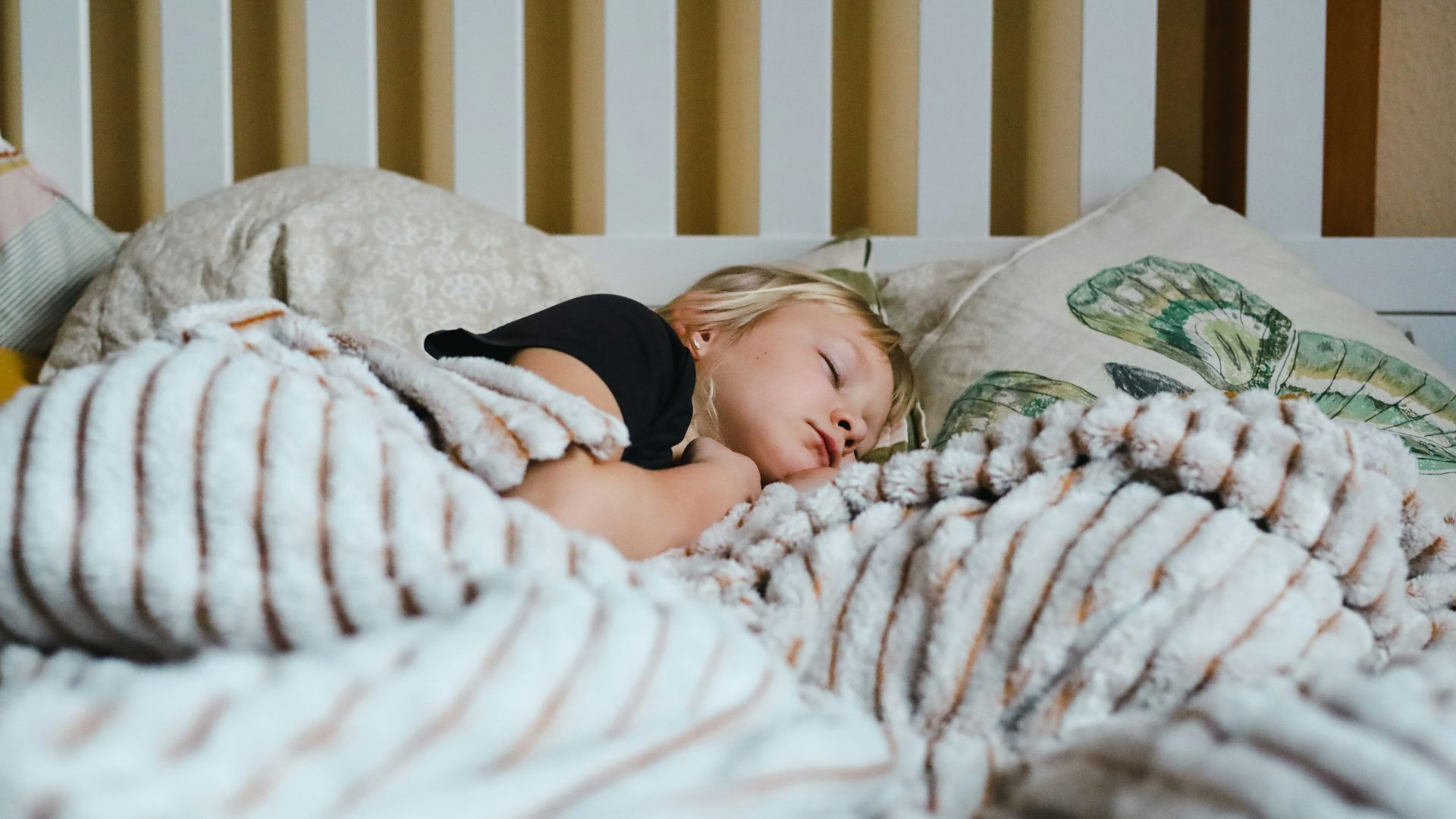 a little girl sleeping in a bed with a blanket