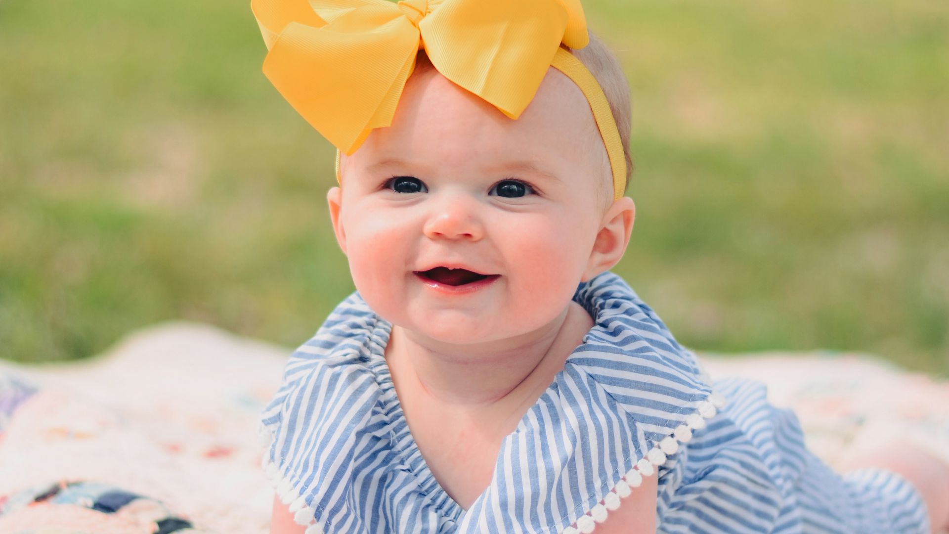 smiling baby lying forward on pink textile