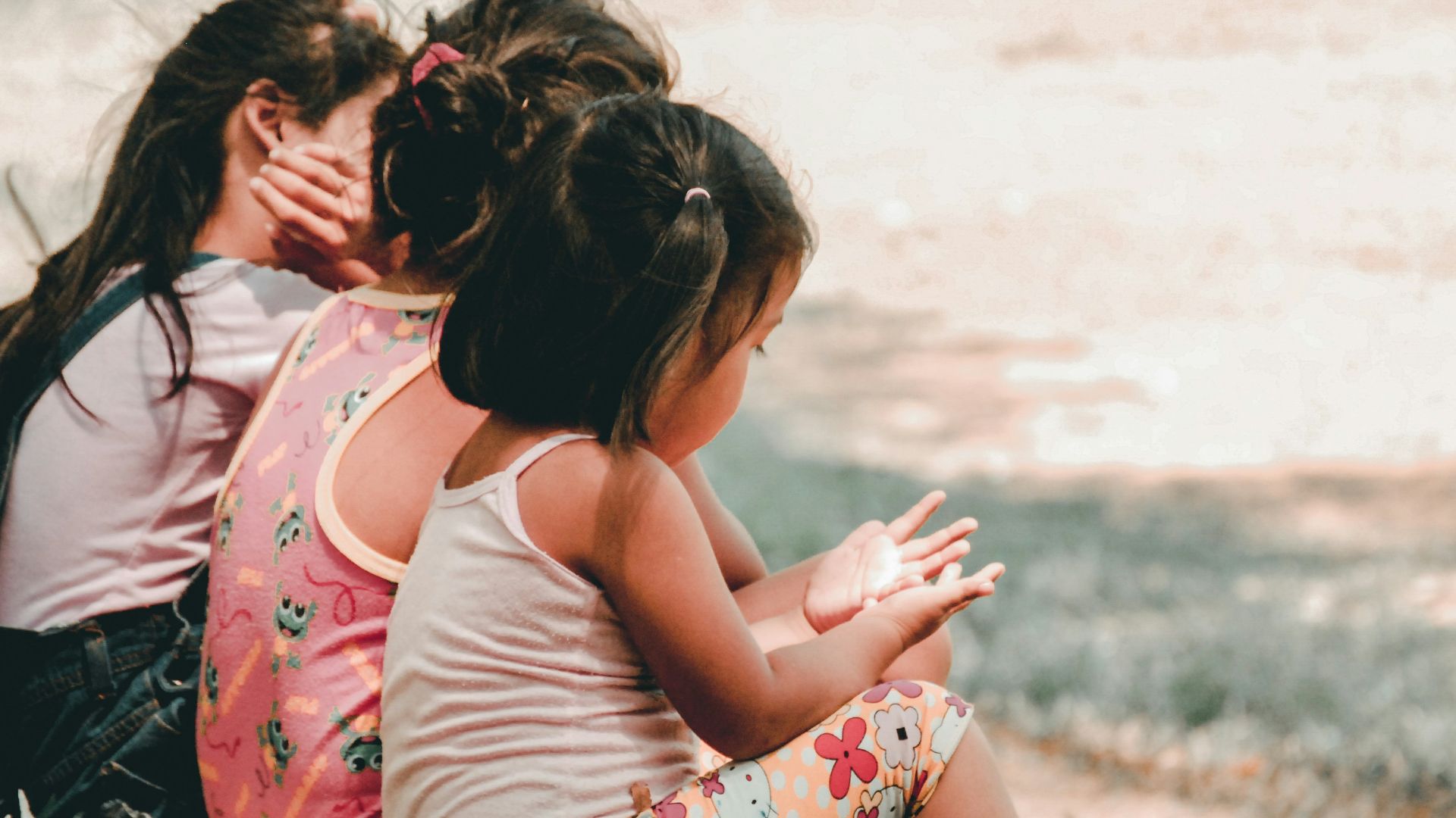 three children sitting on grass