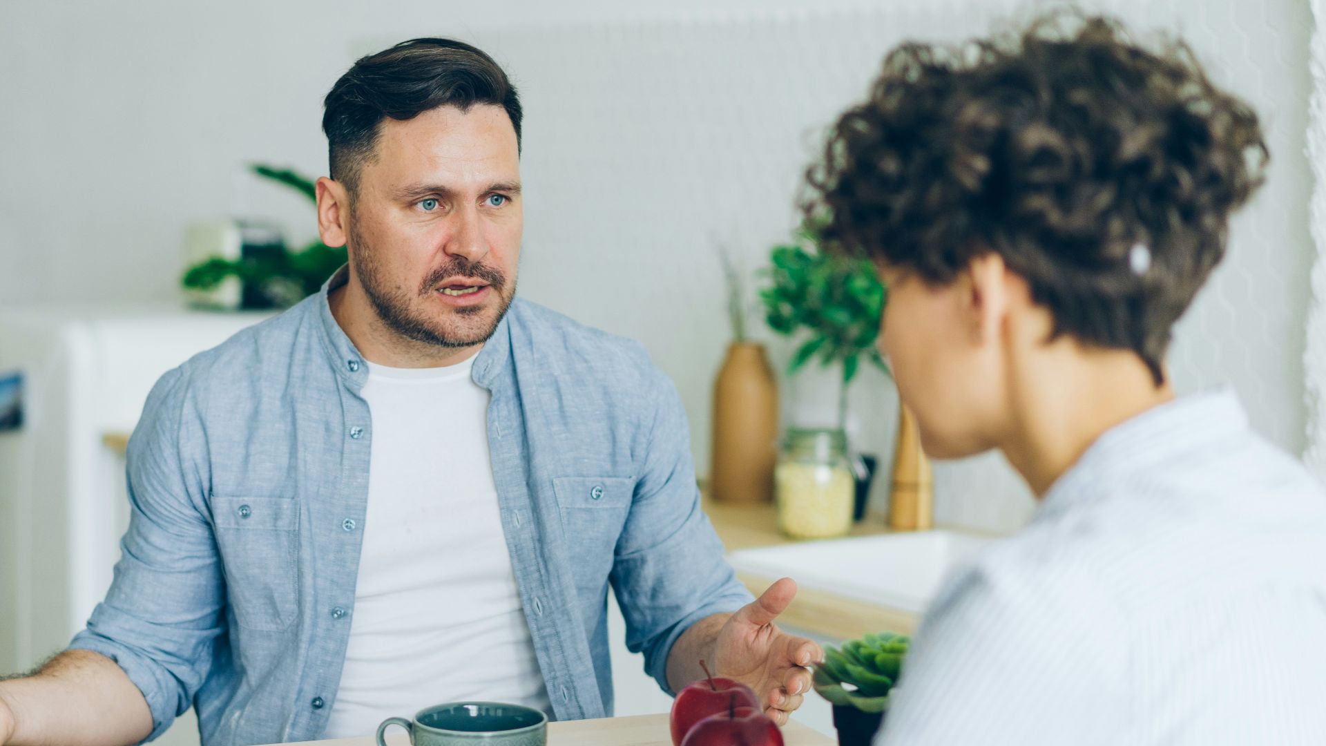 a man sitting at a table talking to a woman