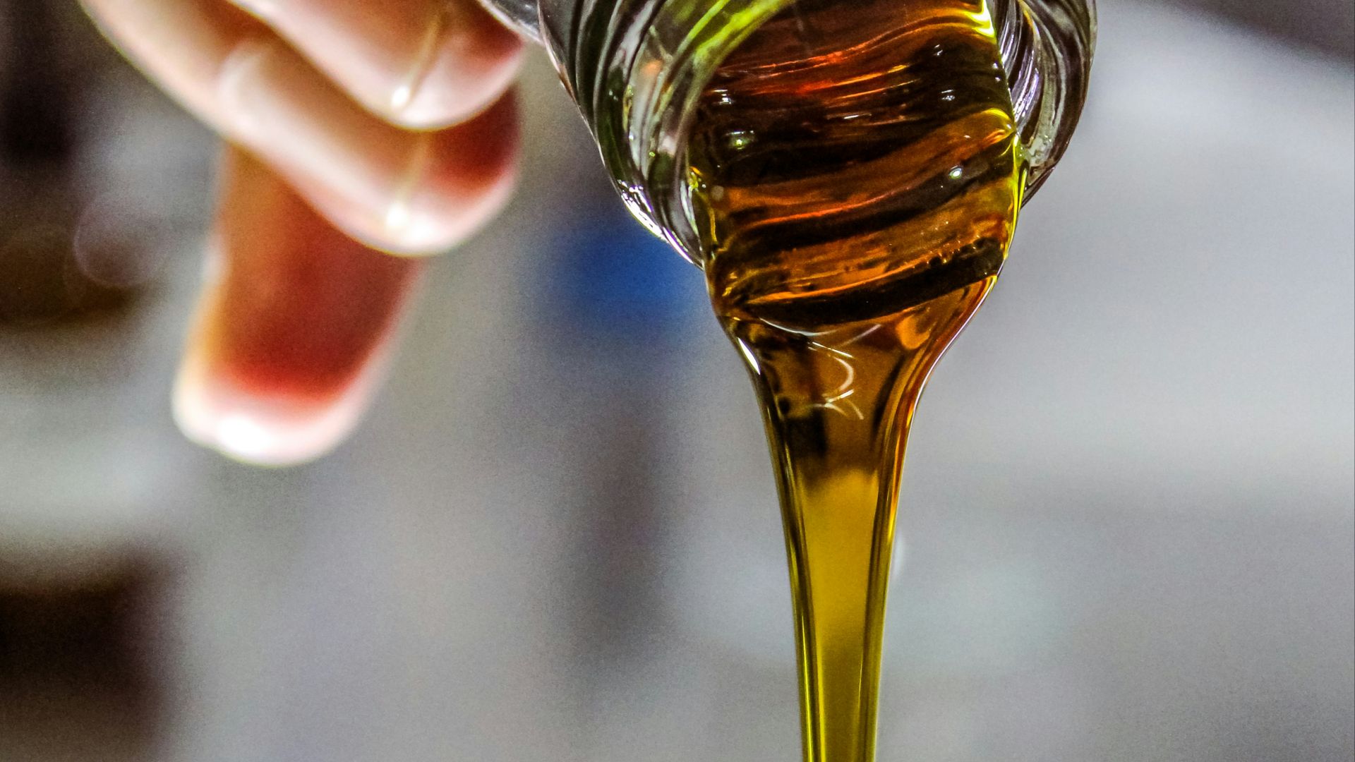person holding clear drinking glass with brown liquid