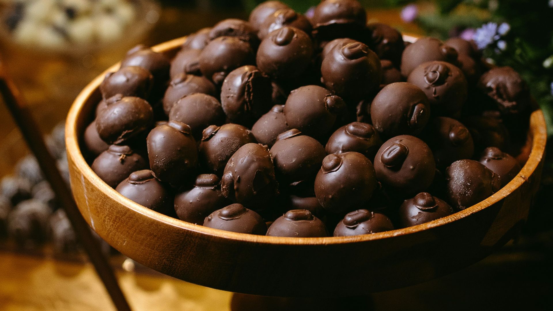 A wooden table topped with a bowl of chocolate