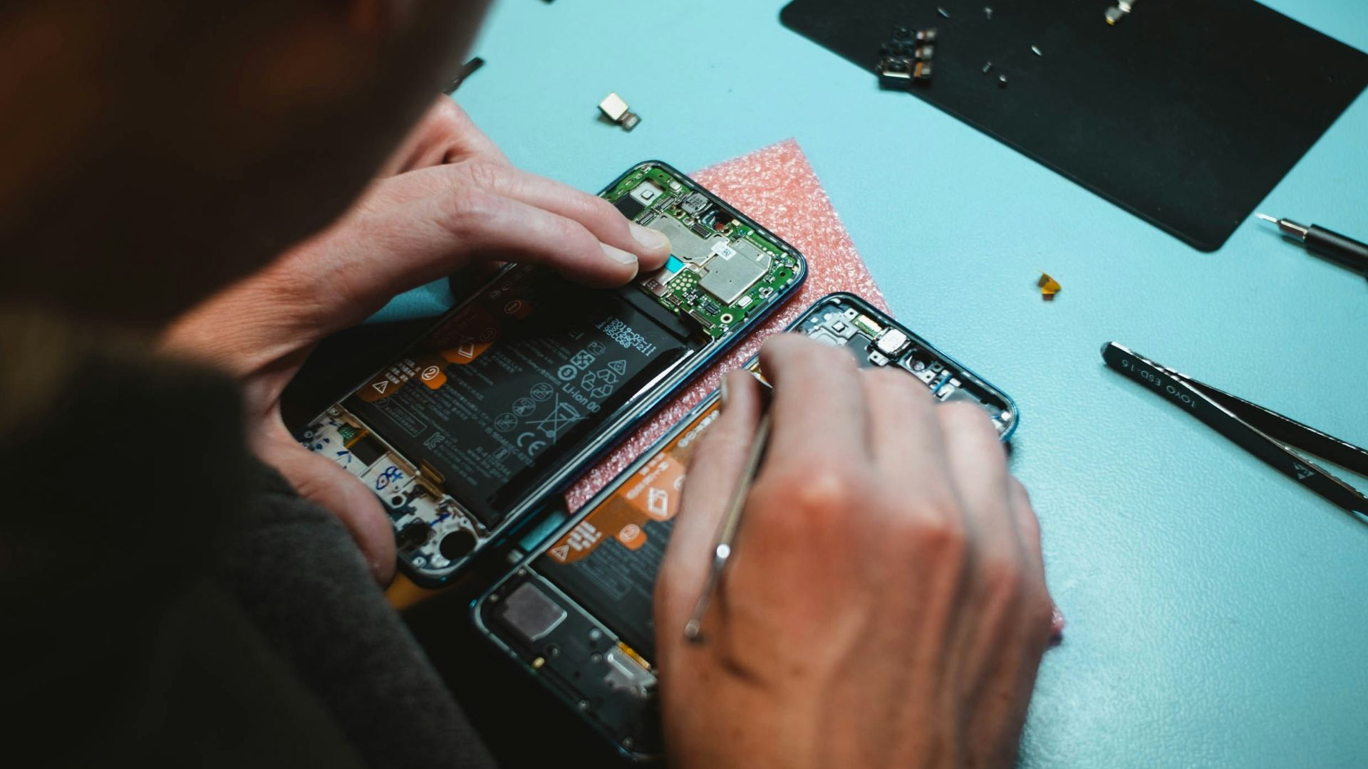 person repairing smartphones under a lighted table