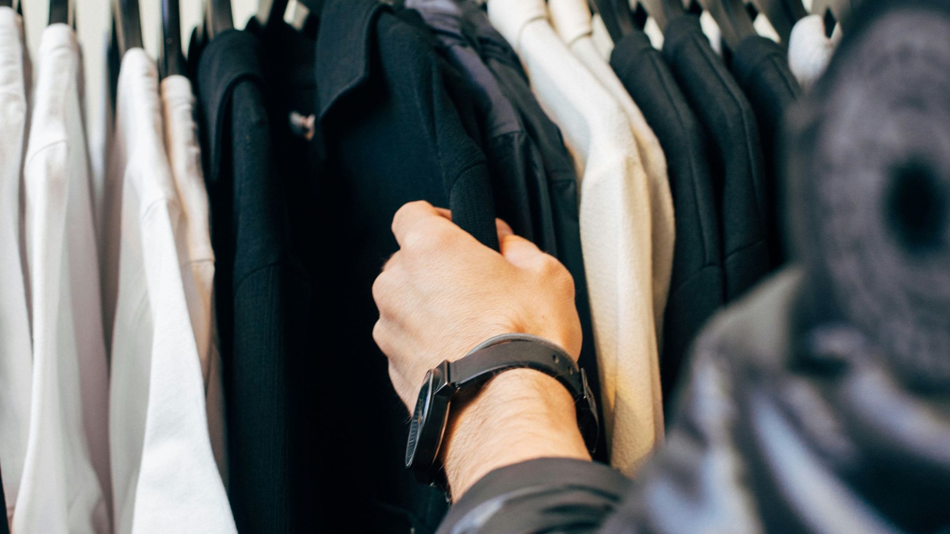 person holding hanged black shirts
