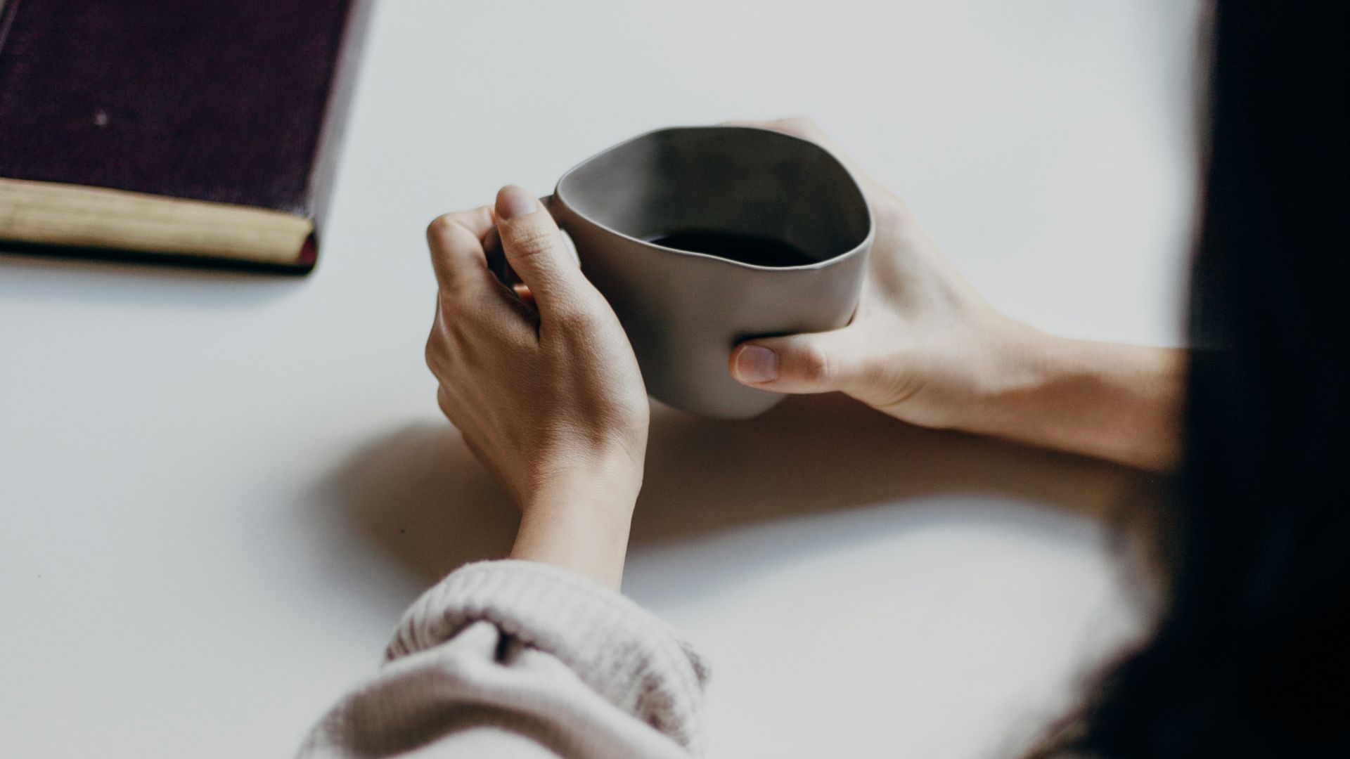 woman in white sweater holding black round frame