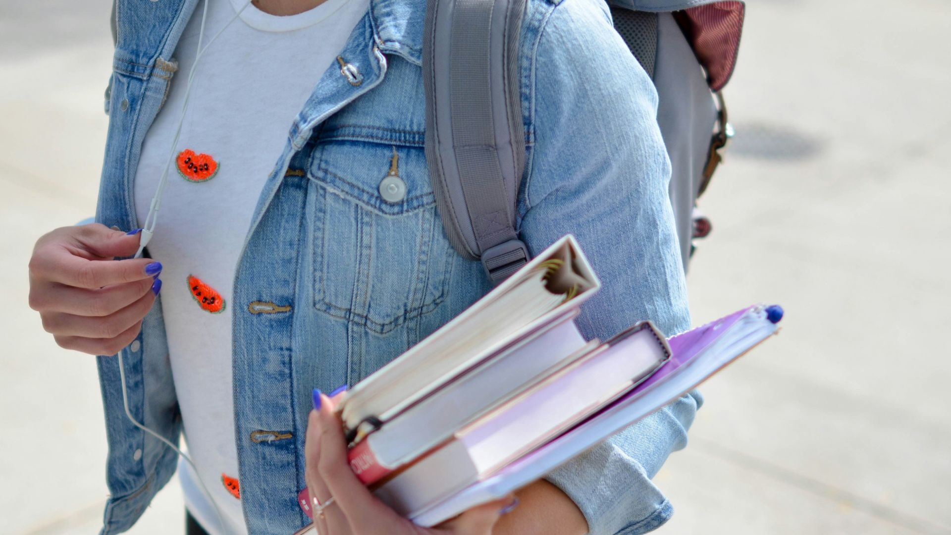 woman wearing blue denim jacket holding book