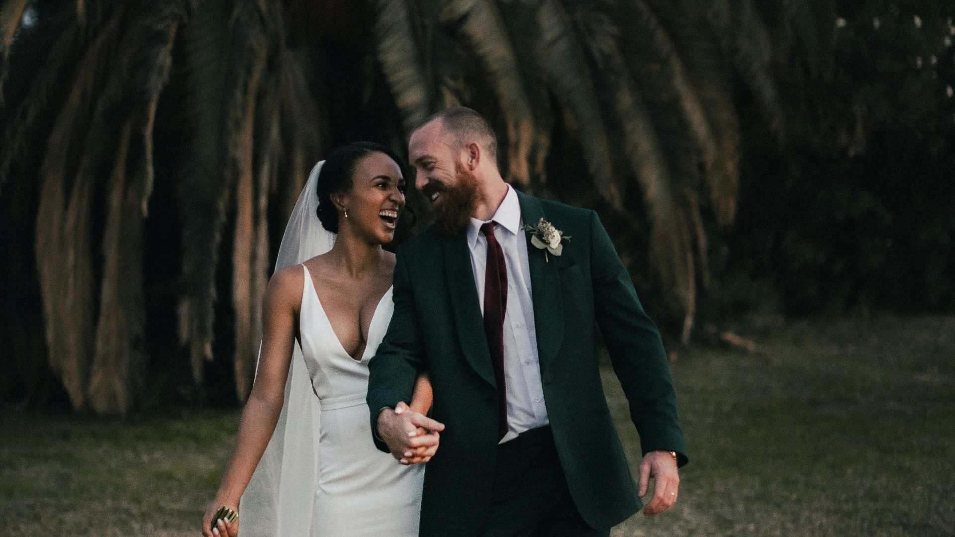 a newly married couple walking through a field