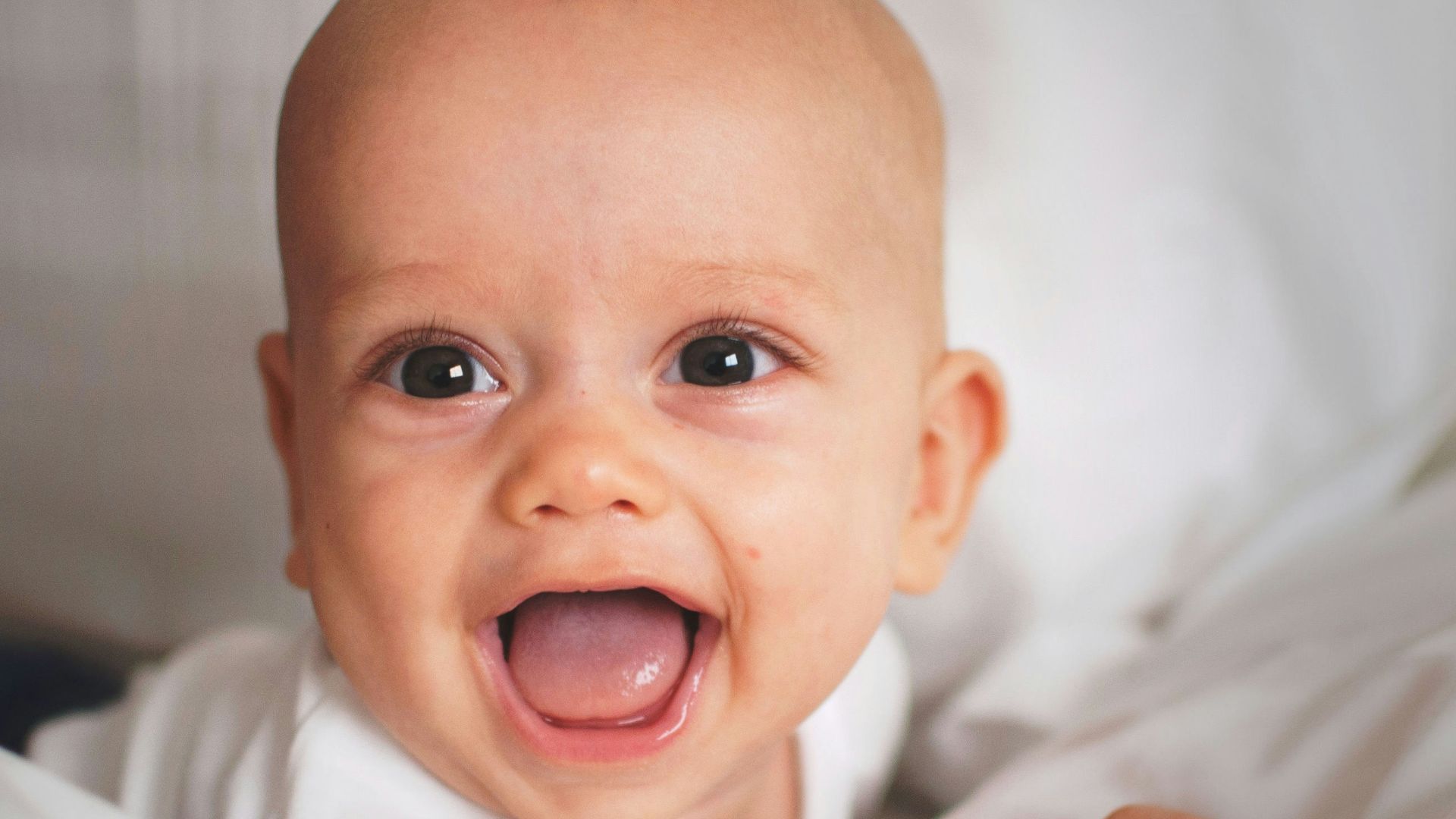 baby smiling on white cushion