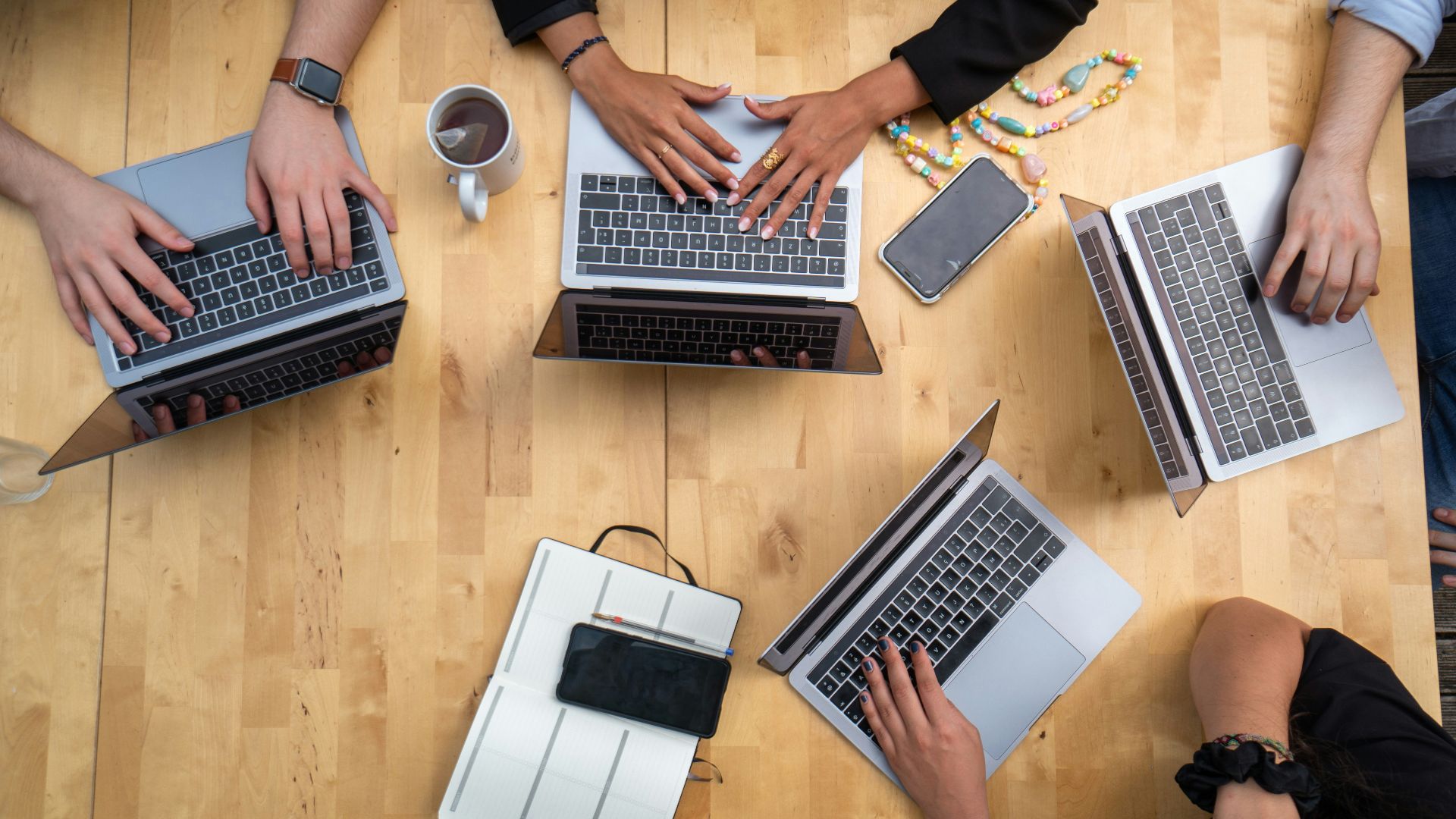 person using macbook pro on brown wooden table