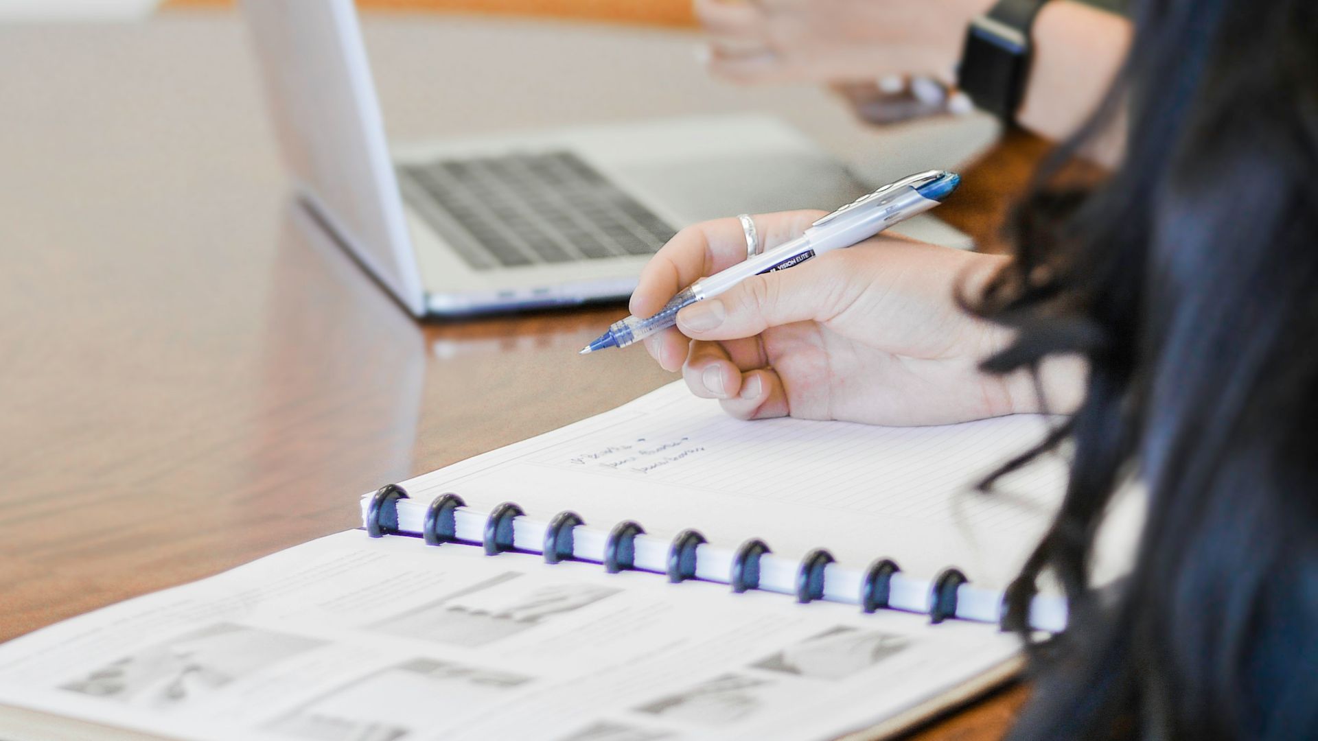 person holding pen writing on paper