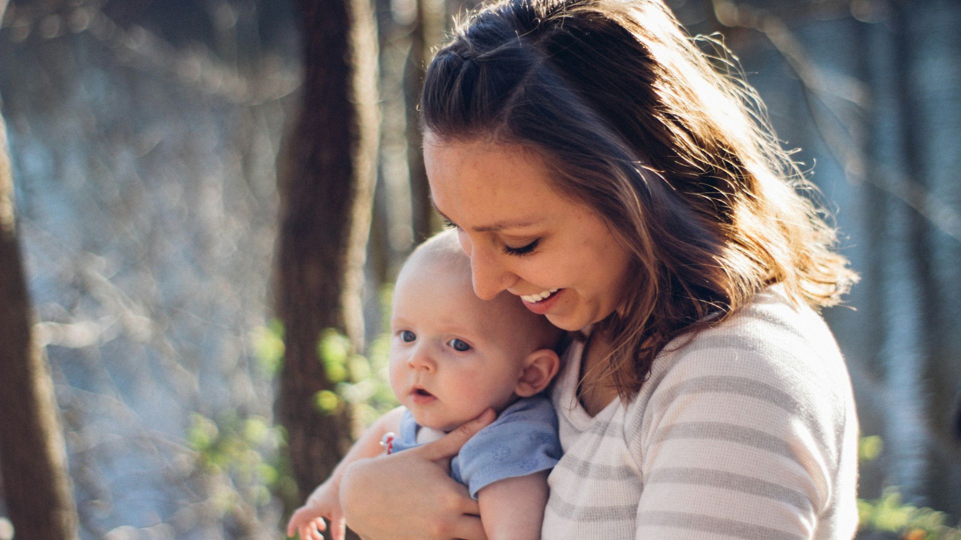 woman carrying baby near trees