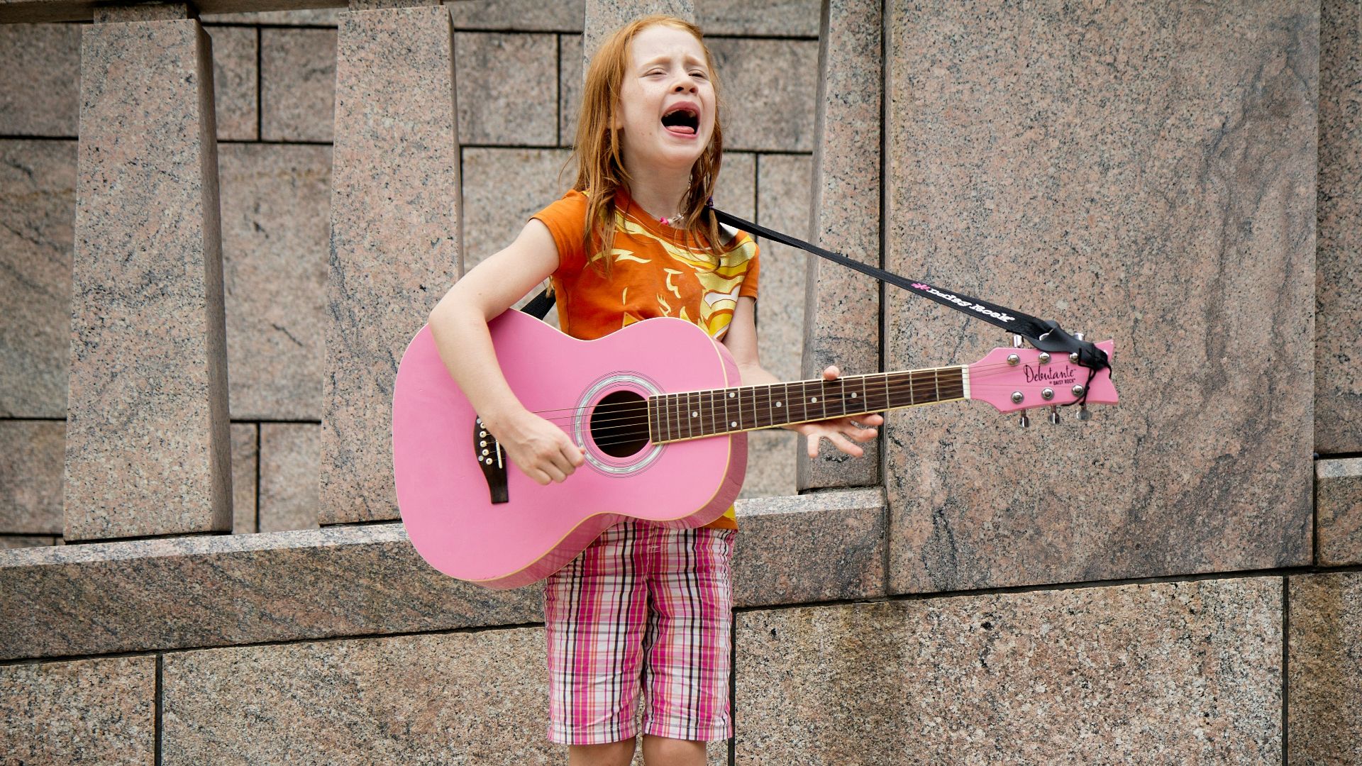 girl playing guitar near wall