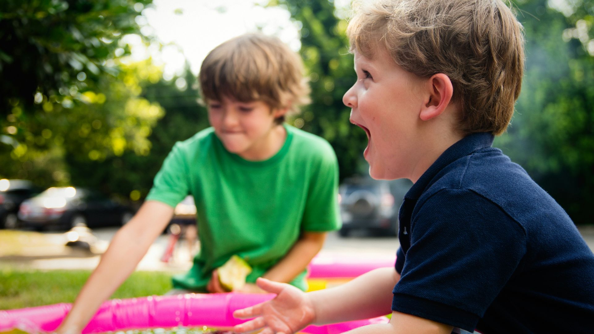 boy in blue shirt screaming near boy in green crew-neck shirt