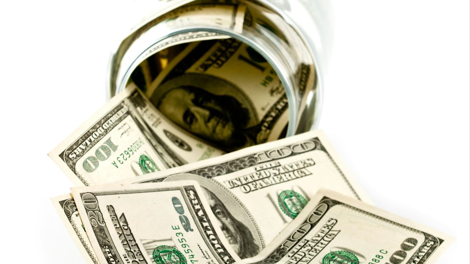 A glass jar filled with money sitting on top of a table